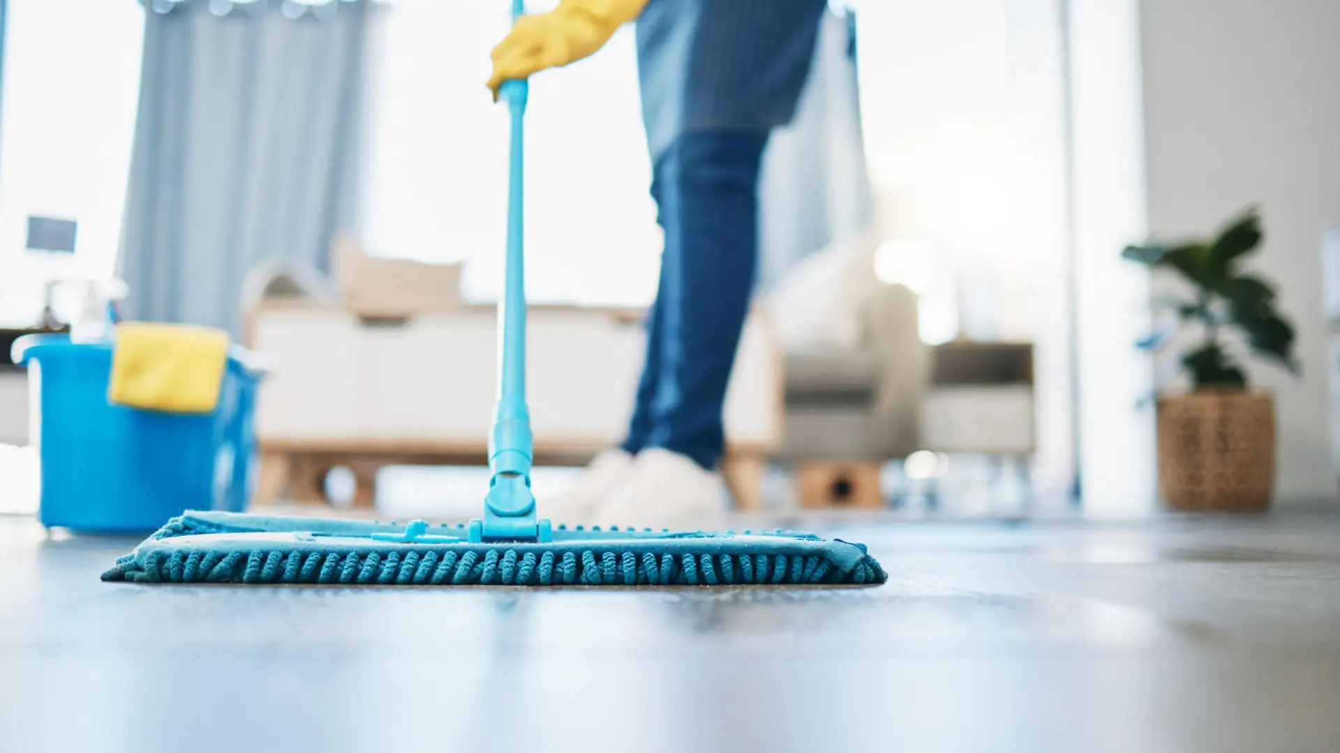 Housekeeping, cleaning and woman maid with a mop to clean the living room floor at a house. Female domestic worker, cleaner and housewife washing the ground for bacteria, dust or dirt in her home.