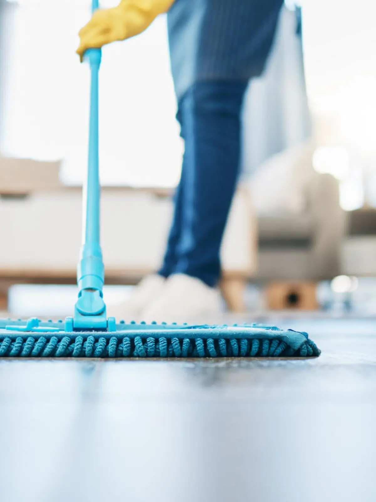 Housekeeping, cleaning and woman maid with a mop to clean the living room floor at a house. Female domestic worker, cleaner and housewife washing the ground for bacteria, dust or dirt in her home.