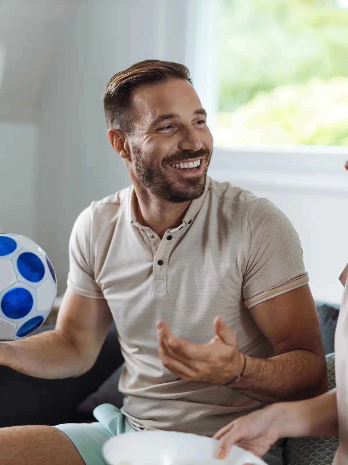 Ein Paar sitzt auf der Couch und schaut Fußball. Die Partnerin schaut genervt. 