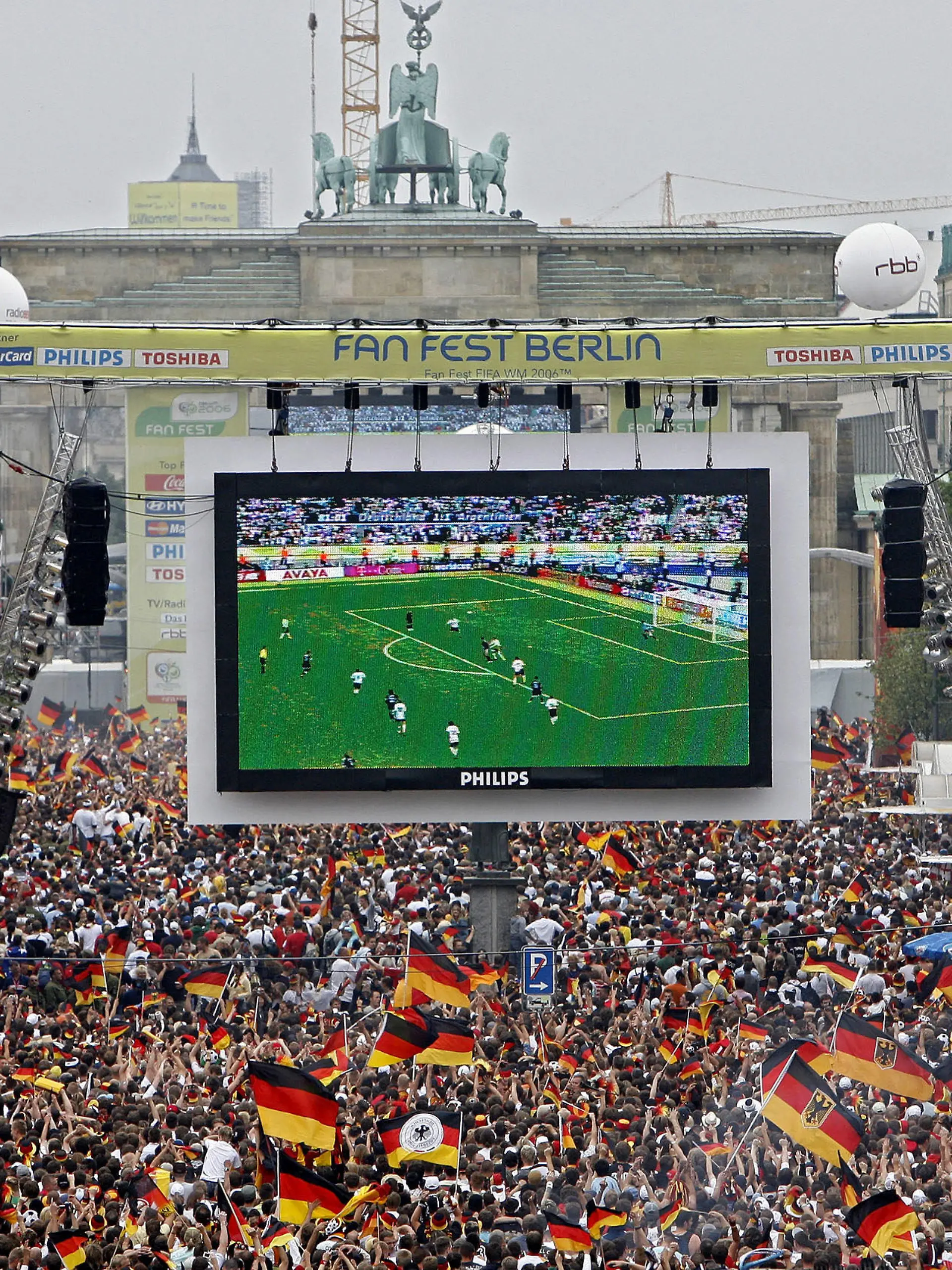 ARCHIV - 30.06.2006, NA, Berlin: Tausende Zuschauer verfolgen auf der Fanmeile am Brandenburger Tor in Berlin das WM-Fußballspiel zwischen Deutschland und Argentinien. Die Fußball-EM wird für die Stadt Berlin deutlich teurer als gedacht. (zu dpa: «Produktion der Fanmeilen in Berlin kostet rund 24 Millionen Euro») Foto: Marcel Mettelsiefen/dpa +++ dpa-Bildfunk +++