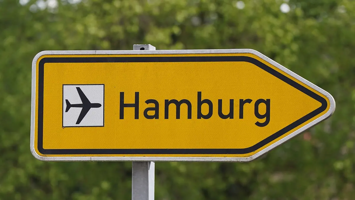 Ein Wegweiser weist an einer Straße den Weg zum Flughafen Hamburg Airport.