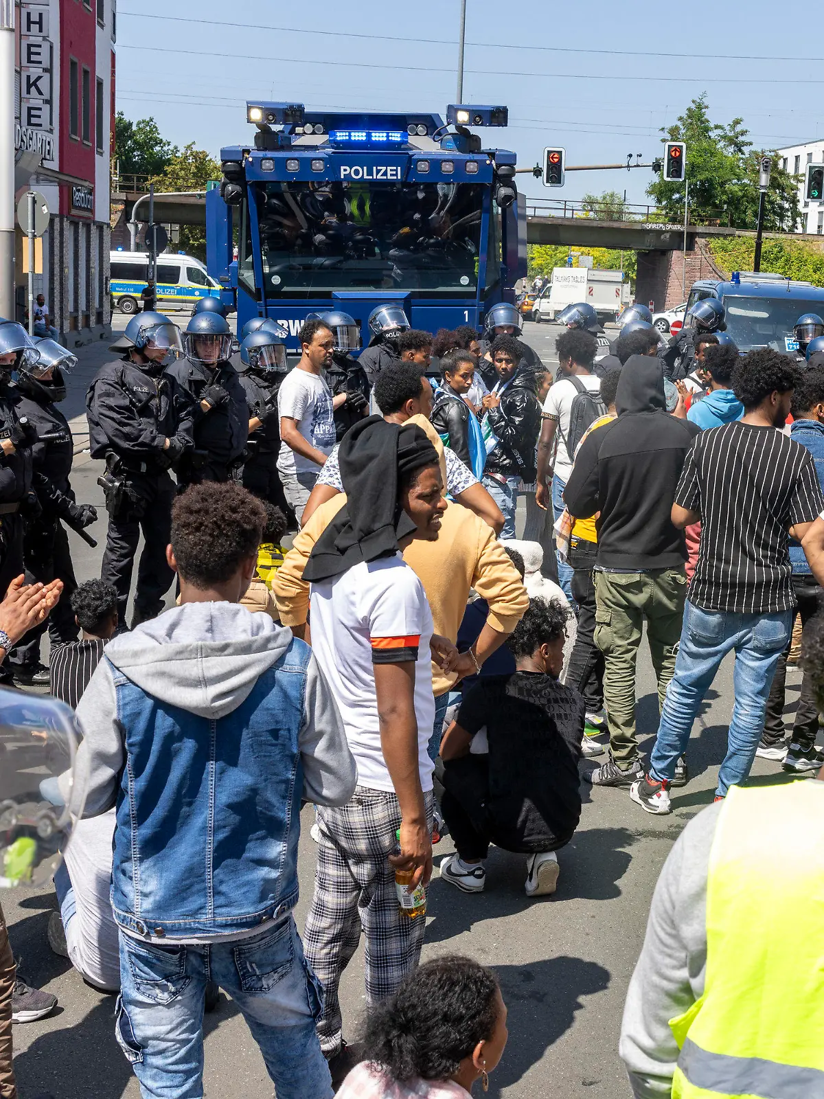 08.07.2023, Hessen, Gießen: Polizisten haben am Rande des Eritrea-Festivals in Gießen eine Gruppe von Menschen umringt und im Hintergrund steht ein Wasserwerfer bereit. Im Zusammenhang mit dem umstrittenen Eritrea-Festival in Gießen hat die Polizei am Samstag Schlagstöcke und Pfefferspray eingesetzt. Mehrere Menschen hätten versucht, eine Polizeikette zu durchbrechen, teilten die Beamten auf Twitter mit. Foto: Helmut Fricke/dpa +++ dpa-Bildfunk +++
