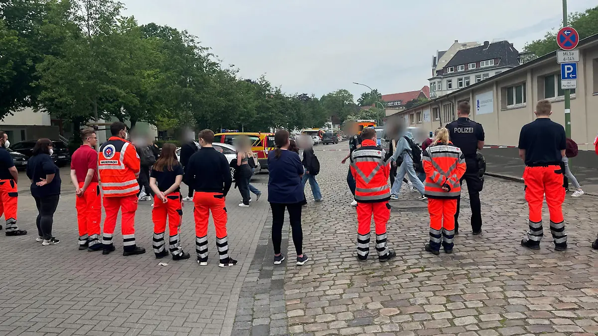 Die Schüler des Gymnasiums verlassen am Mittag das Gebäude und werden dabei von Rettungskräften und bewaffneten Polizisten abgeschirmt.