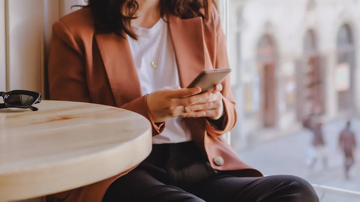 Frau sitzt mit ihrem Smartphone im Cafe.