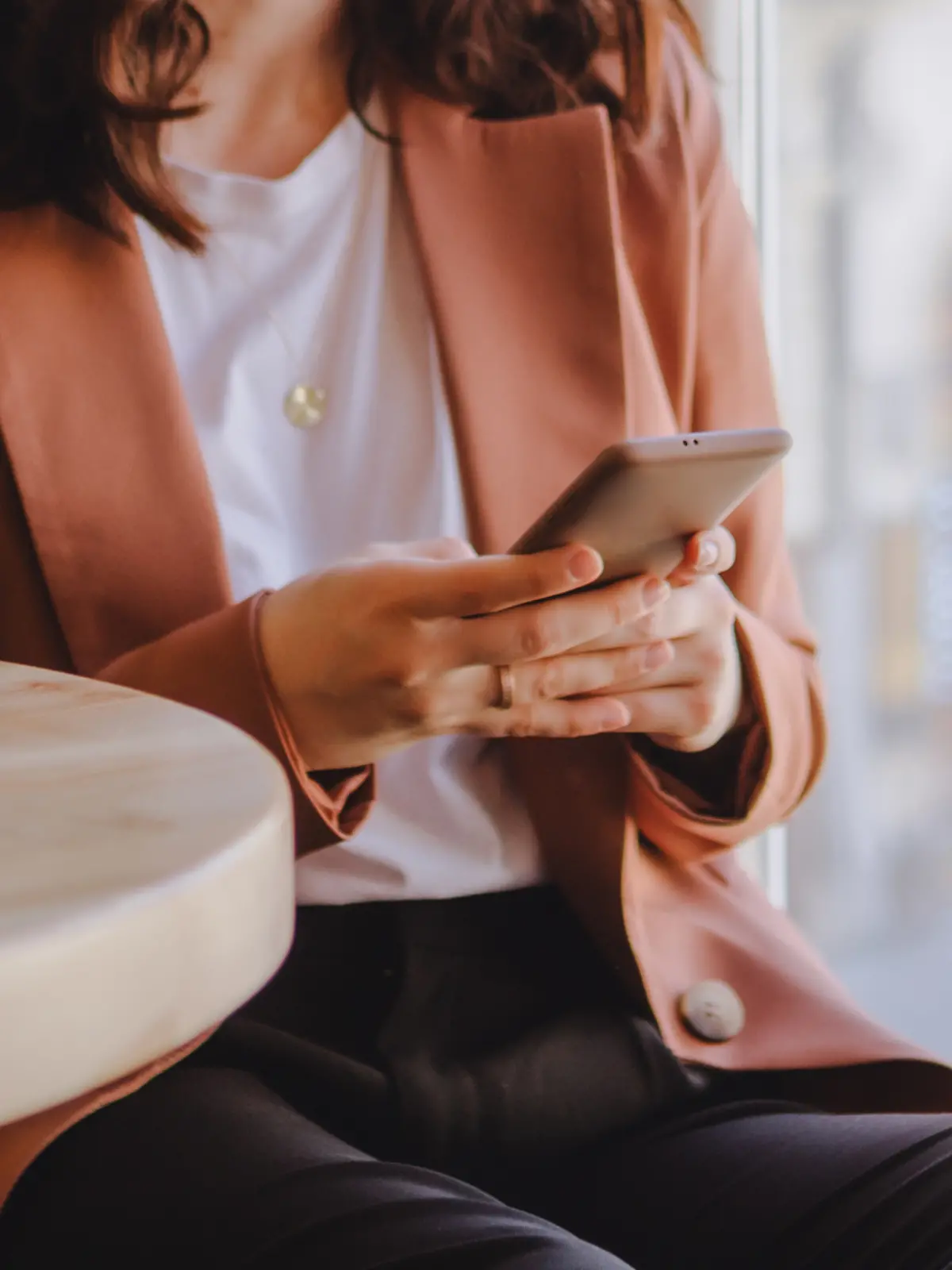 Frau sitzt mit ihrem Smartphone im Cafe.