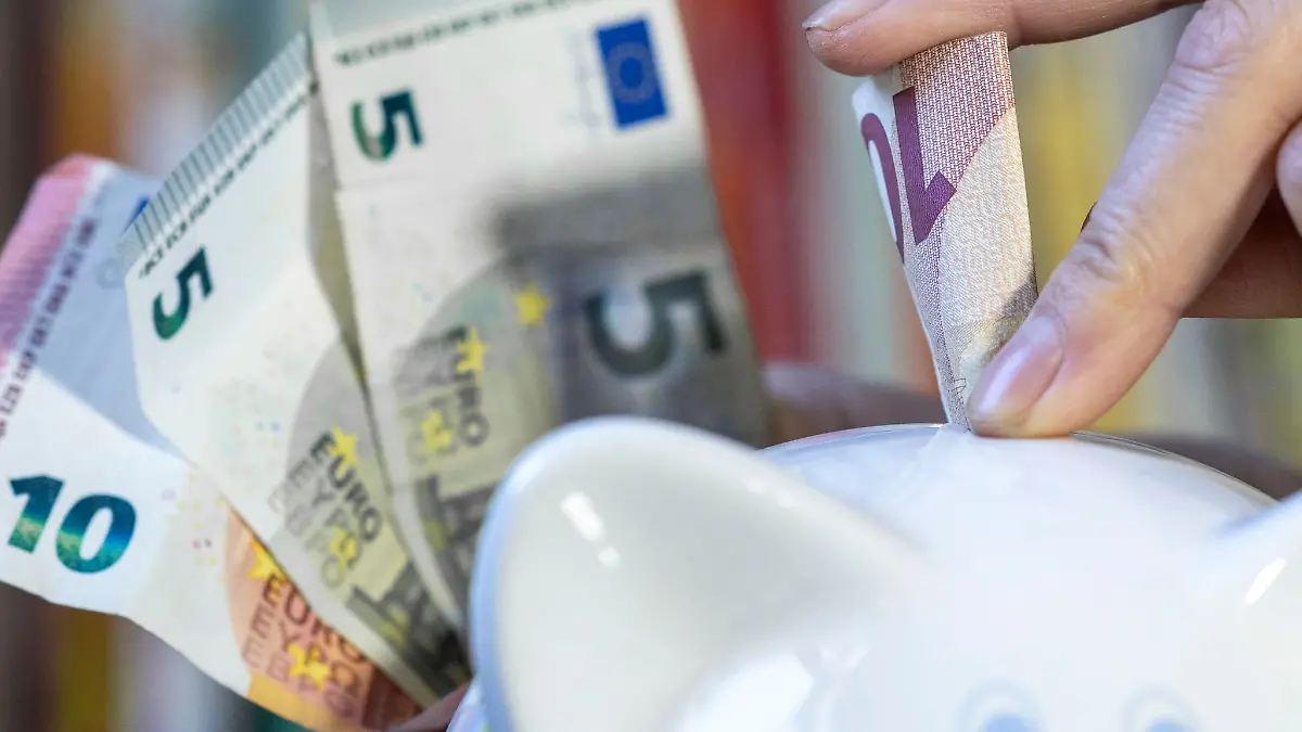 Eine Frau steckt einen 10 Euroschein in ein Sparschwein.