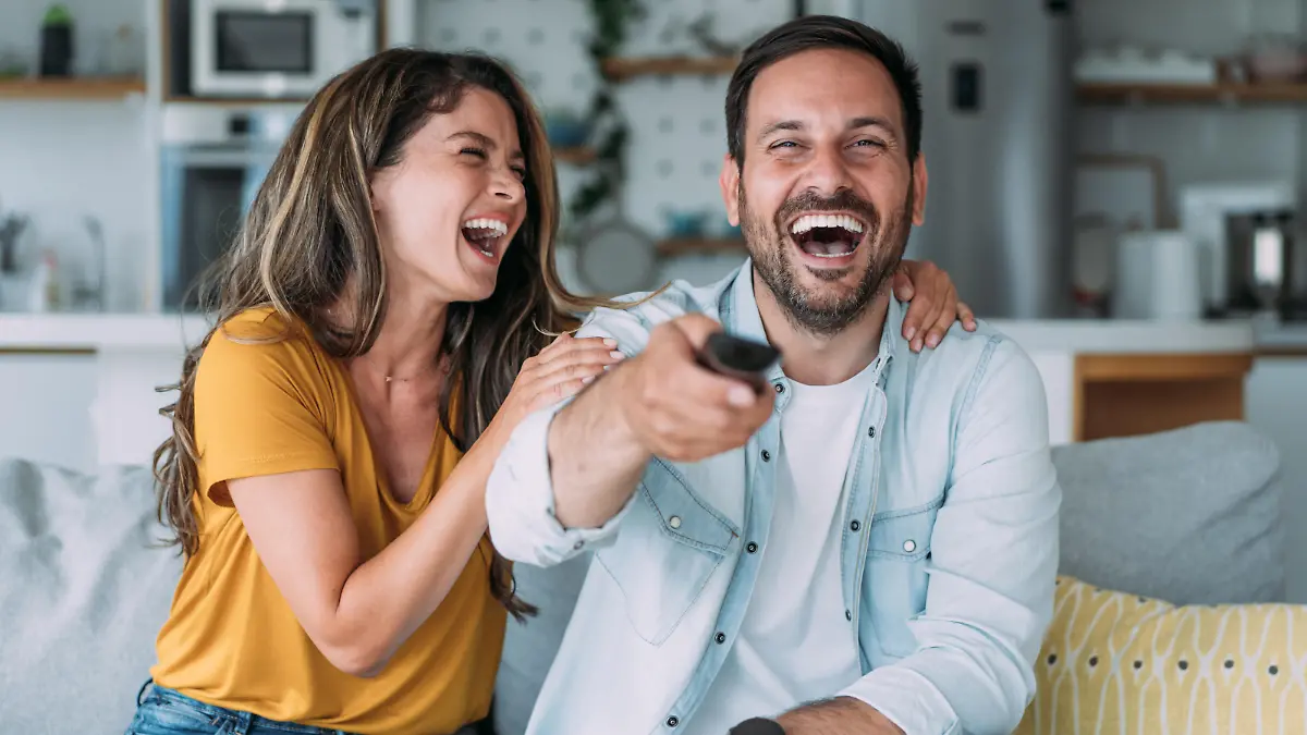 Shot of a beautiful young happy couple sitting on a couch at home and watching tv.