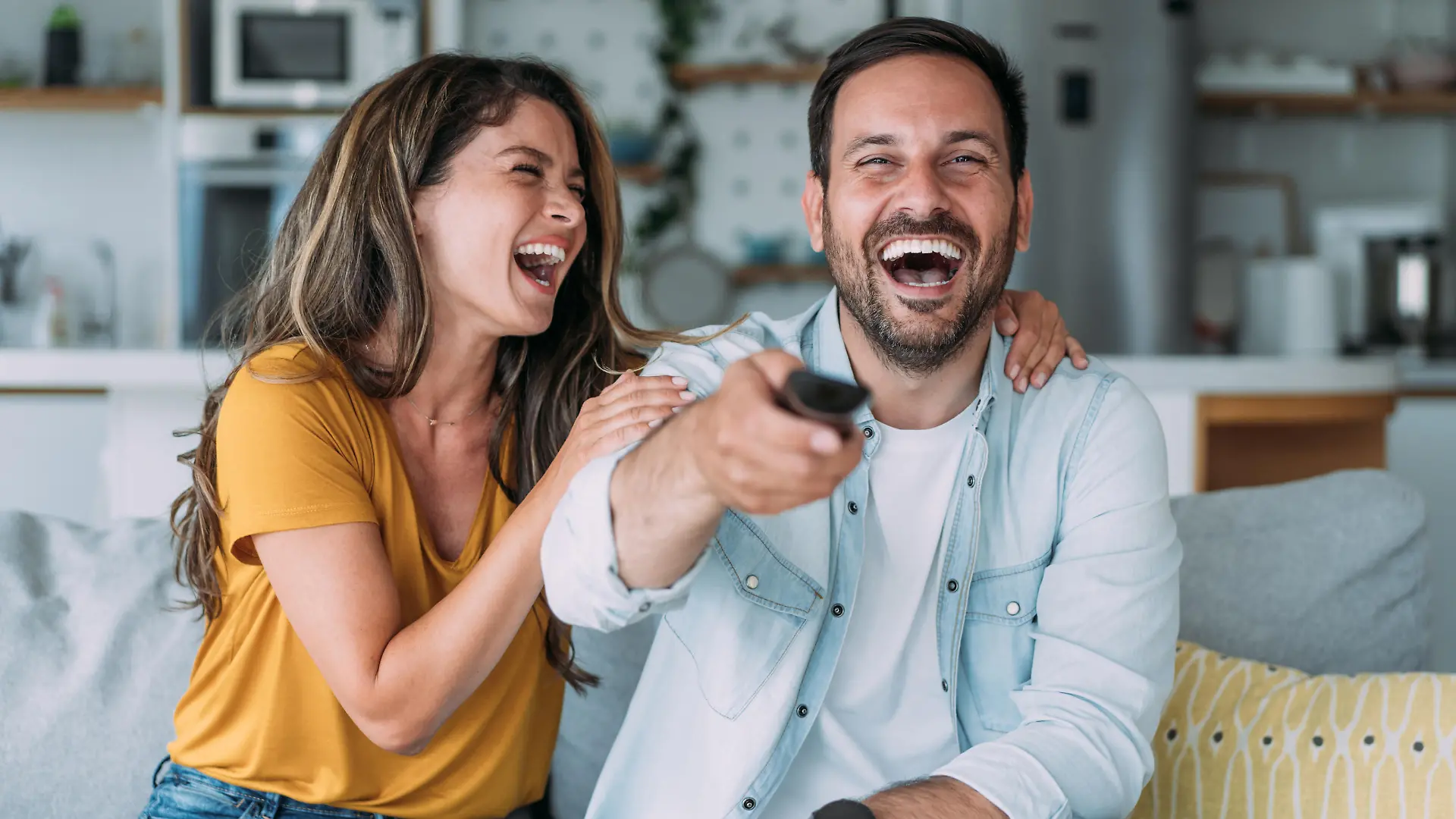 Shot of a beautiful young happy couple sitting on a couch at home and watching tv.