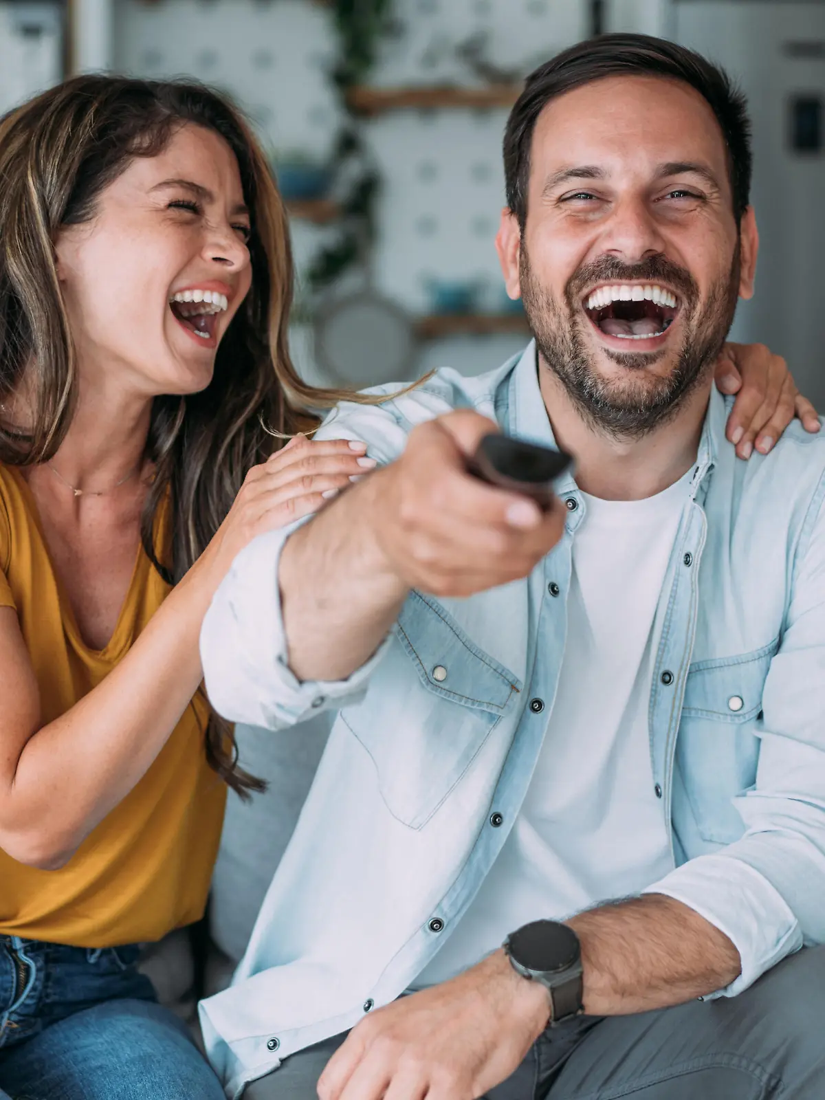 Shot of a beautiful young happy couple sitting on a couch at home and watching tv.