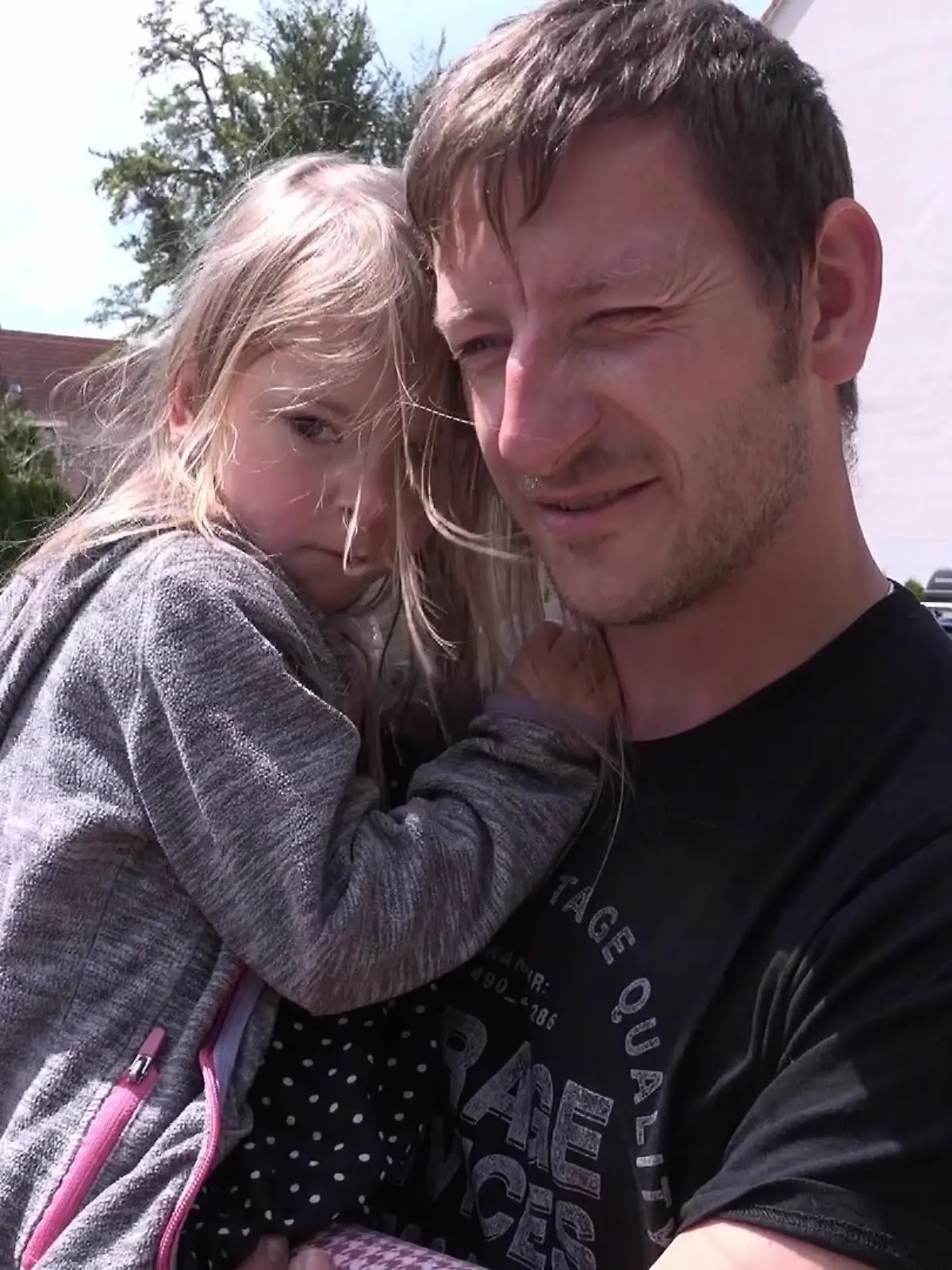 Ein Vater trägt seine kleine Tochter auf dem Arm.