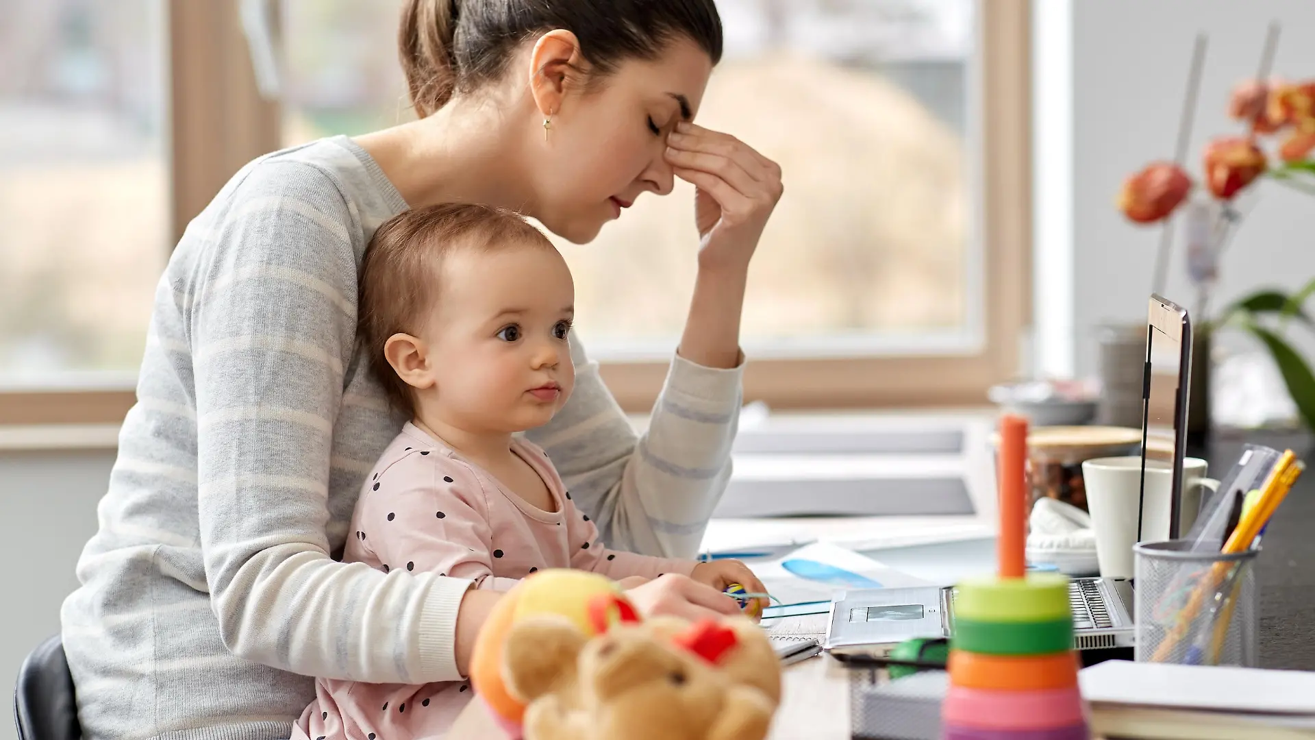 remote job, multi-tasking and family concept - tired mother with baby working at home office