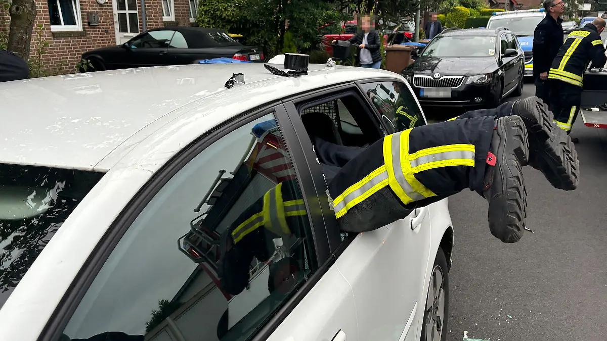 Ein Feuerwehrmann klettert im niederrheinischen Goch in ein Auto, in dem sich ein Kleinkind eingeschlossen hatte.
