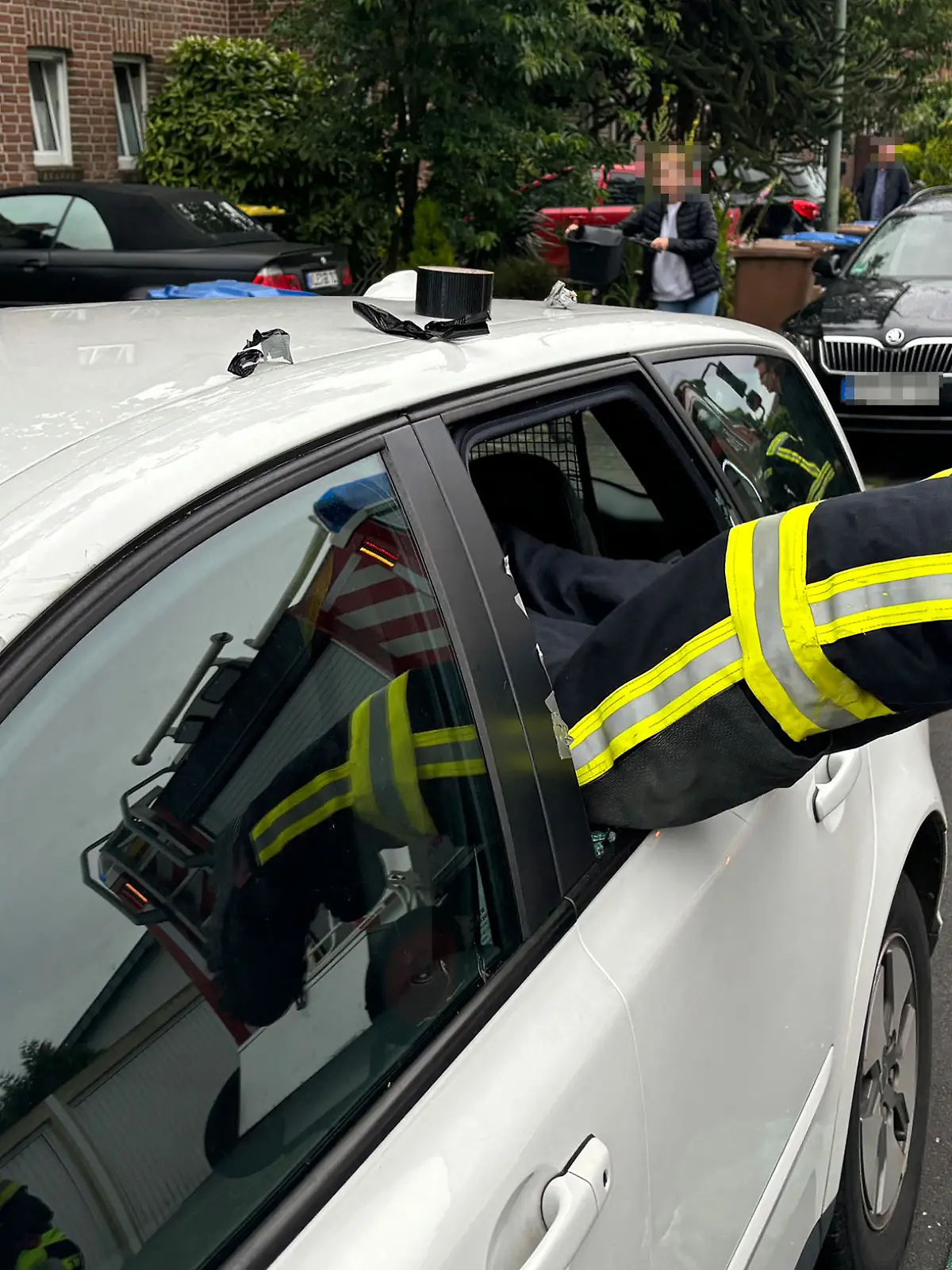 Ein Feuerwehrmann klettert im niederrheinischen Goch in ein Auto, in dem sich ein Kleinkind eingeschlossen hatte.   