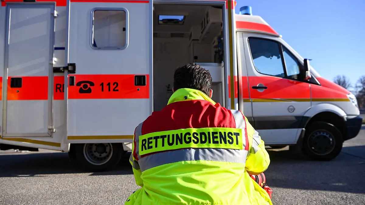 «Rettungsdienst» steht auf der Jacke eines Mannes vor einem Rettungswagen der Feuerwehr.