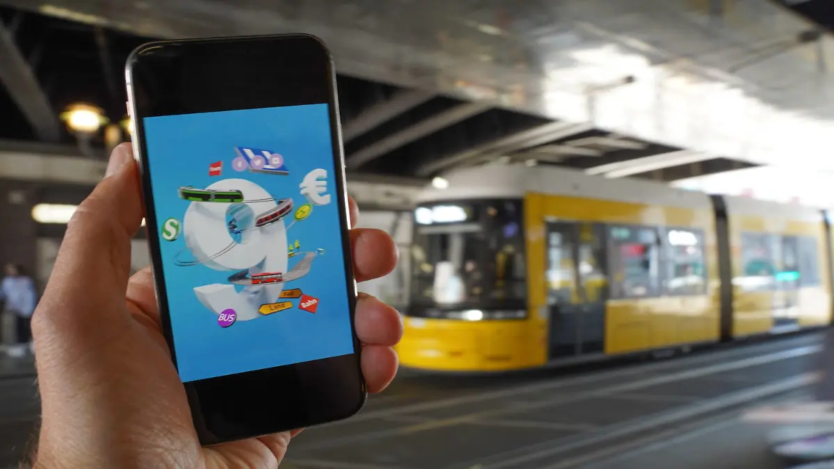 18.05.2022, Berlin: Ein Smartphone, auf dem eine Werbung für das 9-Euro-Ticket zu sehen ist, wird vor eine Tram gehalten. Die Sondertickets sollen im Juni, Juli und August bundesweit Fahrten im Nah- und Regionalverkehr ermöglichen. Der Bundestag soll das Finanzierungsgesetz an diesem Donnerstag beschließen, am Freitag soll der Bundesrat abschließend entscheiden. Foto: Jörg Carstensen/dpa +++ dpa-Bildfunk +++