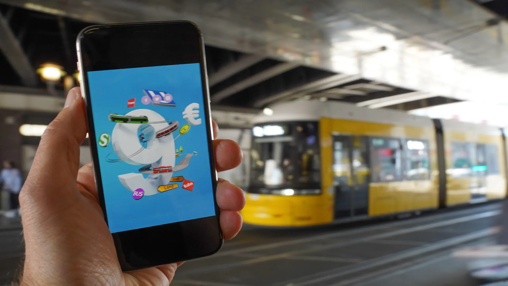 18.05.2022, Berlin: Ein Smartphone, auf dem eine Werbung für das 9-Euro-Ticket zu sehen ist, wird vor eine Tram gehalten. Die Sondertickets sollen im Juni, Juli und August bundesweit Fahrten im Nah- und Regionalverkehr ermöglichen. Der Bundestag soll das Finanzierungsgesetz an diesem Donnerstag beschließen, am Freitag soll der Bundesrat abschließend entscheiden. Foto: Jörg Carstensen/dpa +++ dpa-Bildfunk +++