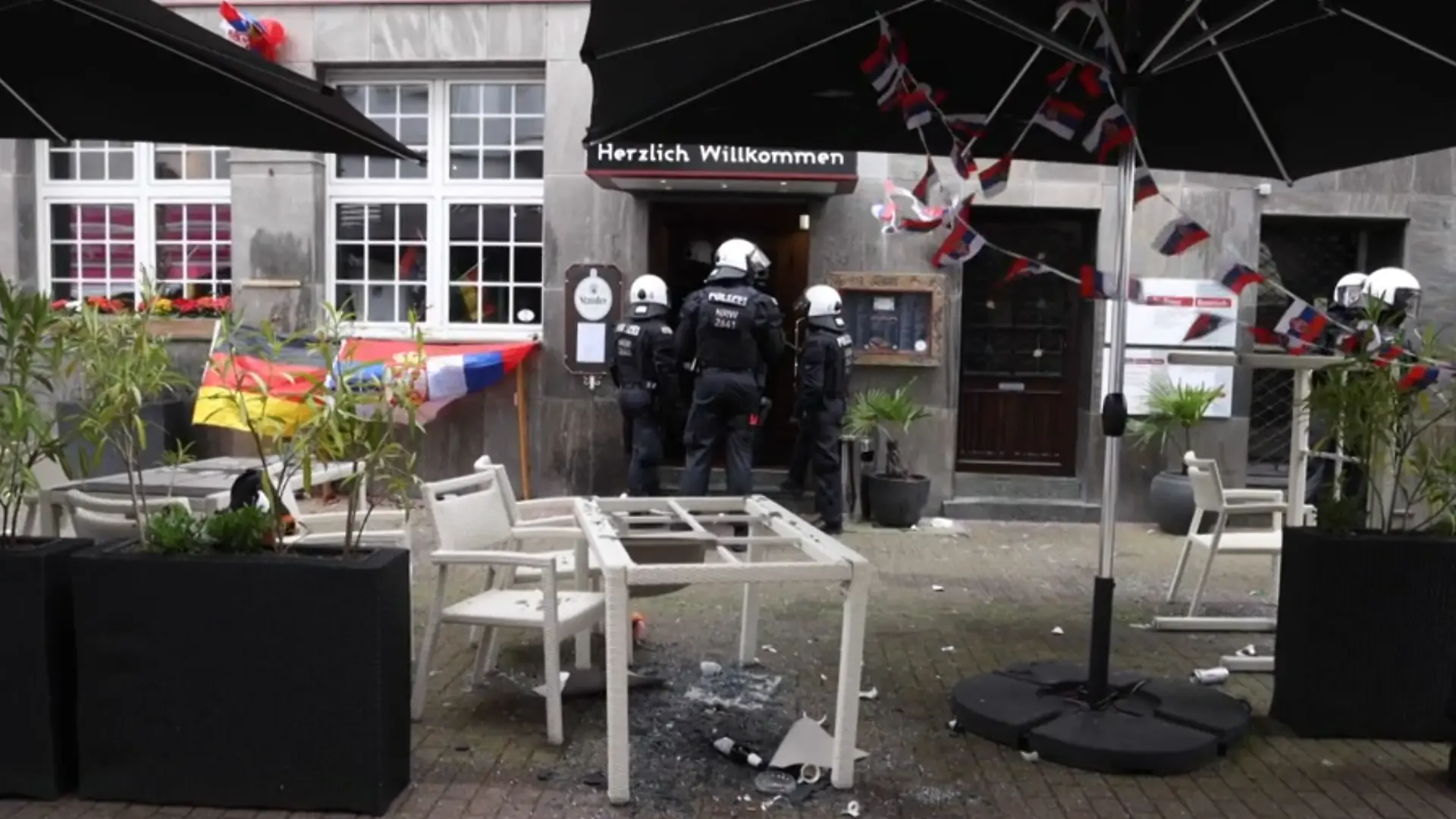 Polizisten stehen vor einem Restaurant, die Terrasse ist verwüstet.