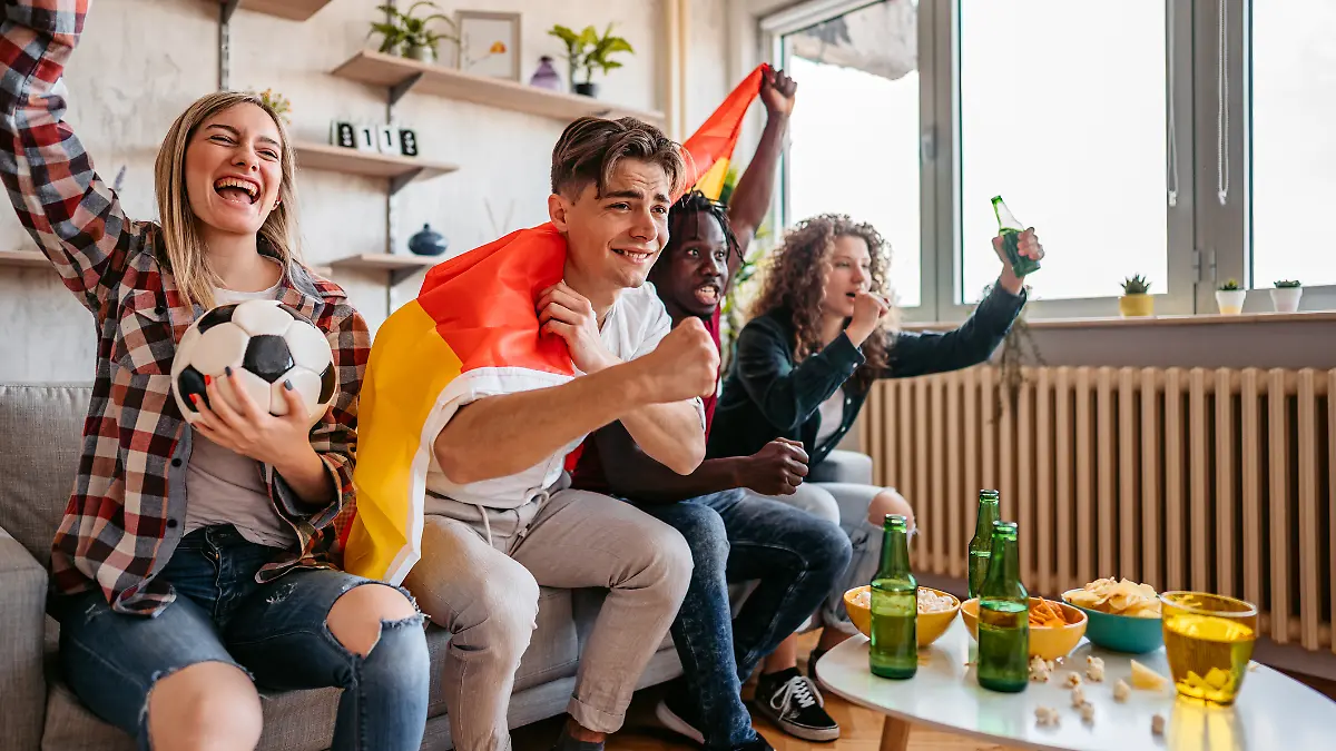 Gruppe Freunde jubelt während des Deutschlandspiels vor dem Fernseher.