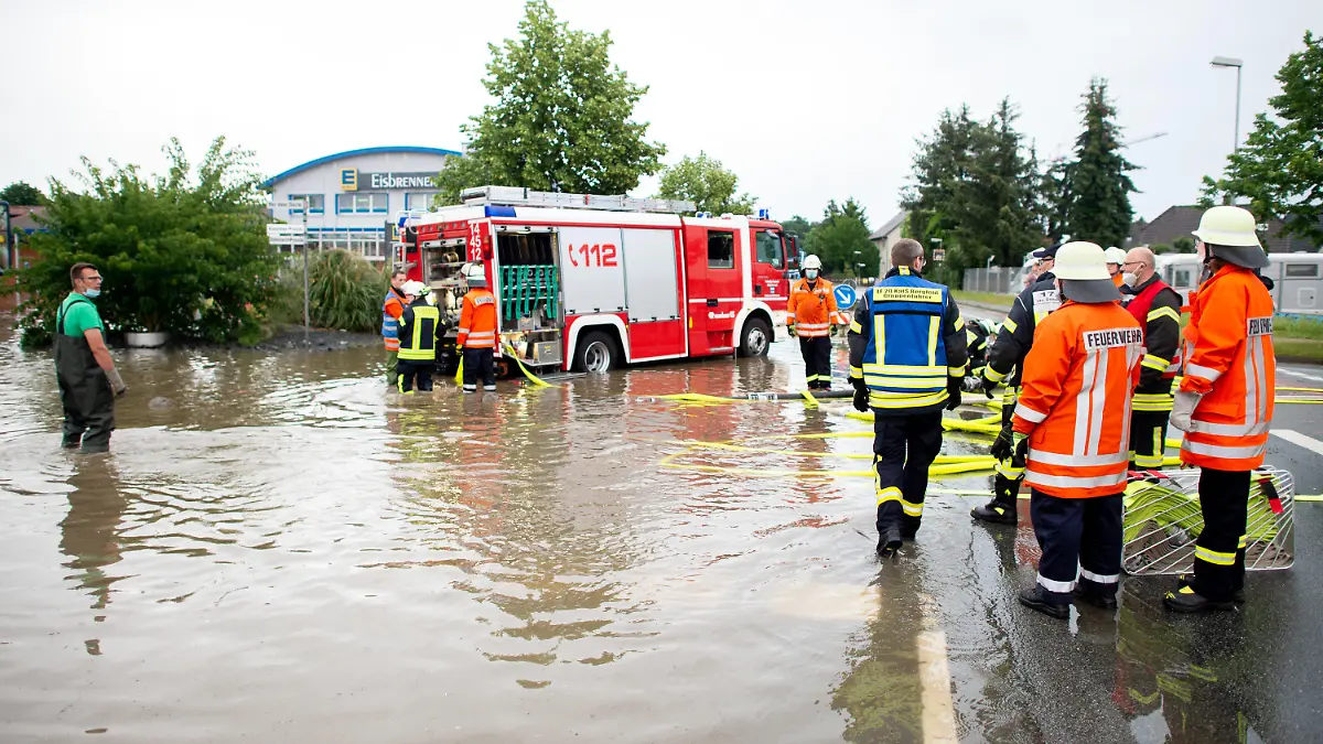 13.06.2020, Niedersachsen, Weyhausen: Ein Einsatzfahrzeug der Feuerwehr steht auf der überschwemmten und gesperrten Bundesstraße B188 im Landkreis Gifhorn vor einem Supermarkt, dessen Parkplatz durch Starkregen überflutet wurde und abgepumpt werden muss. Einzelne Gewitter haben am Samstag in Niedersachsen örtlich heftigen Regen gebracht. Foto: Hauke-Christian Dittrich/dpa +++ dpa-Bildfunk +++