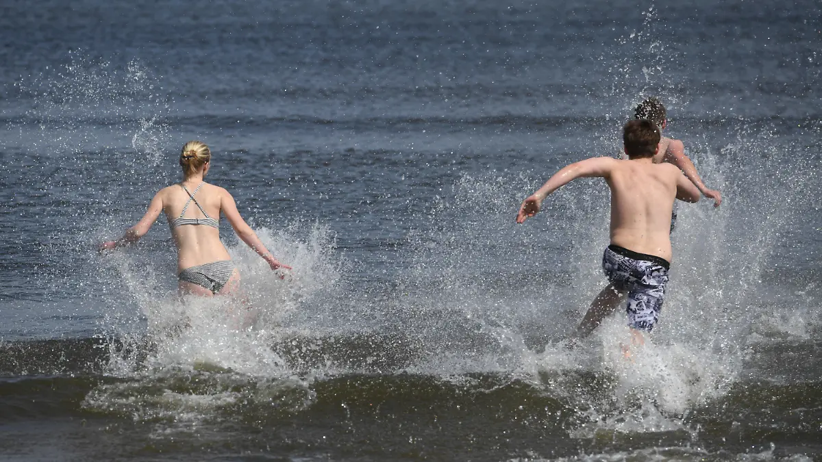 ARCHIV - 01.05.2020, Mecklenburg-Vorpommern, Ahlbeck: Junge Leute laufen bei frühlingshaftem Wetter in die Ostsee. Vor allem in wärmeren Sommern wie 2003, 2018 und 2019 wurden Fälle bekannt, einige Patienten starben: Eine Infektion mit sogenannten Vibrionen kann beim Baden in der Ostsee zur Gefahr werden. Und das künftig wohl viel stärker als bisher. (zu dpa «Folge der Erderwärmung: Mehr Infektionen mit Vibrionen erwartet») Foto: Stefan Sauer/dpa +++ dpa-Bildfunk +++