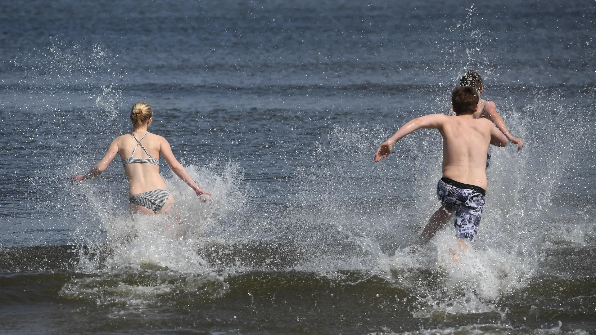 ARCHIV - 01.05.2020, Mecklenburg-Vorpommern, Ahlbeck: Junge Leute laufen bei frühlingshaftem Wetter in die Ostsee. Vor allem in wärmeren Sommern wie 2003, 2018 und 2019 wurden Fälle bekannt, einige Patienten starben: Eine Infektion mit sogenannten Vibrionen kann beim Baden in der Ostsee zur Gefahr werden. Und das künftig wohl viel stärker als bisher. (zu dpa «Folge der Erderwärmung: Mehr Infektionen mit Vibrionen erwartet») Foto: Stefan Sauer/dpa +++ dpa-Bildfunk +++