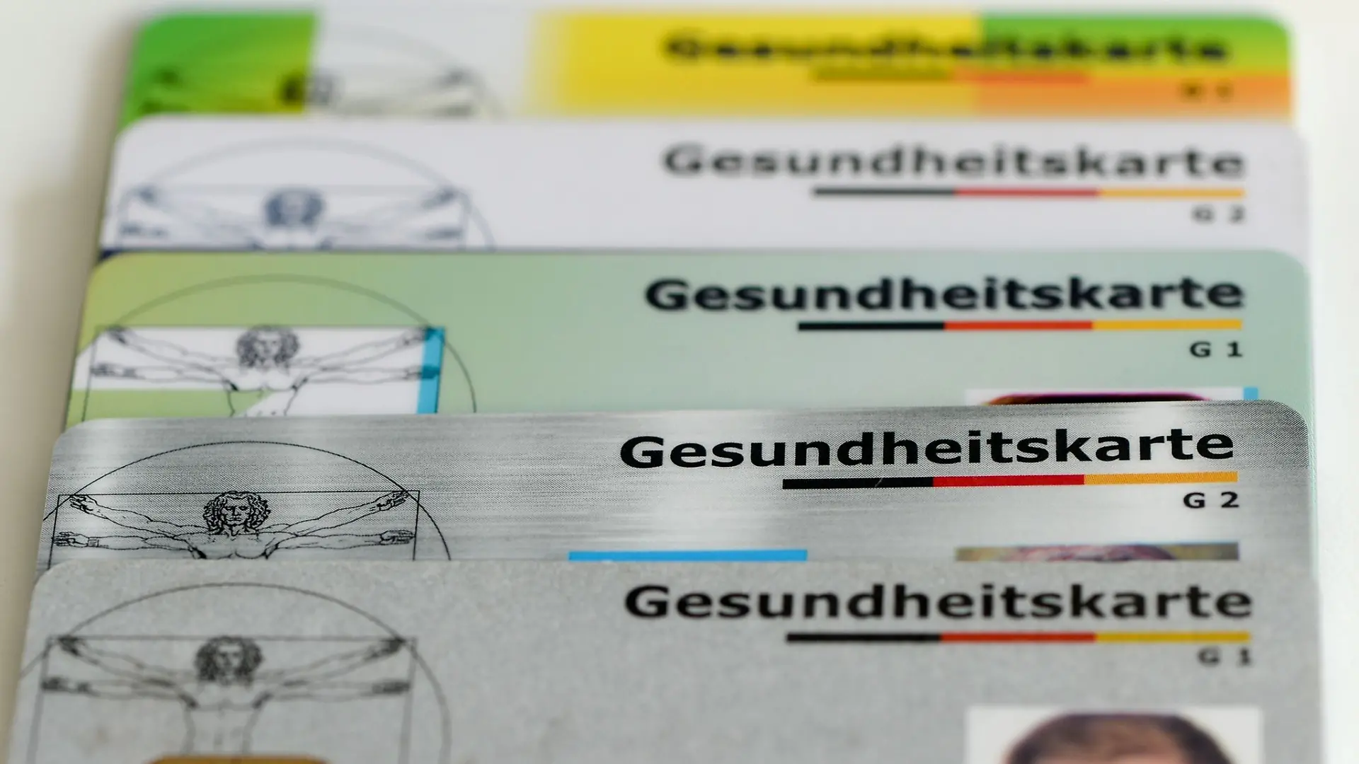 Gesundheitskarten verschiedener Krankenkassen liegen auf einem Tisch.