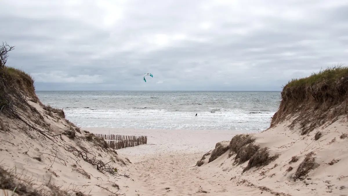 20.06.2021, Schleswig-Holstein, Rantum/Sylt: Ein Kitesurfer ist auf der Nordseeinsel am Strand von Rantum auf der Nordsee unterwegs, über der dunkle Wolken hängen. Foto: Daniel Bockwoldt/dpa/Daniel Bockwoldt +++ dpa-Bildfunk +++