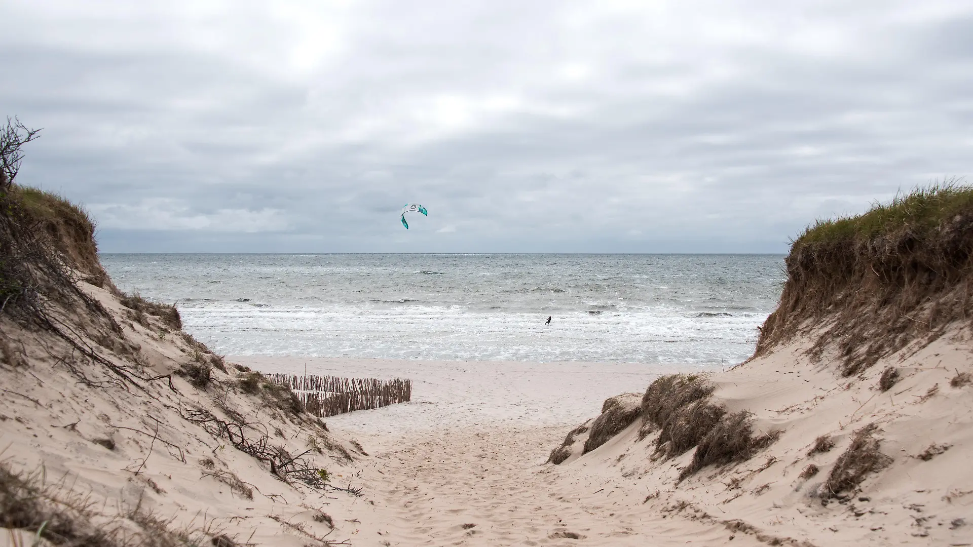 20.06.2021, Schleswig-Holstein, Rantum/Sylt: Ein Kitesurfer ist auf der Nordseeinsel am Strand von Rantum auf der Nordsee unterwegs, über der dunkle Wolken hängen. Foto: Daniel Bockwoldt/dpa/Daniel Bockwoldt +++ dpa-Bildfunk +++