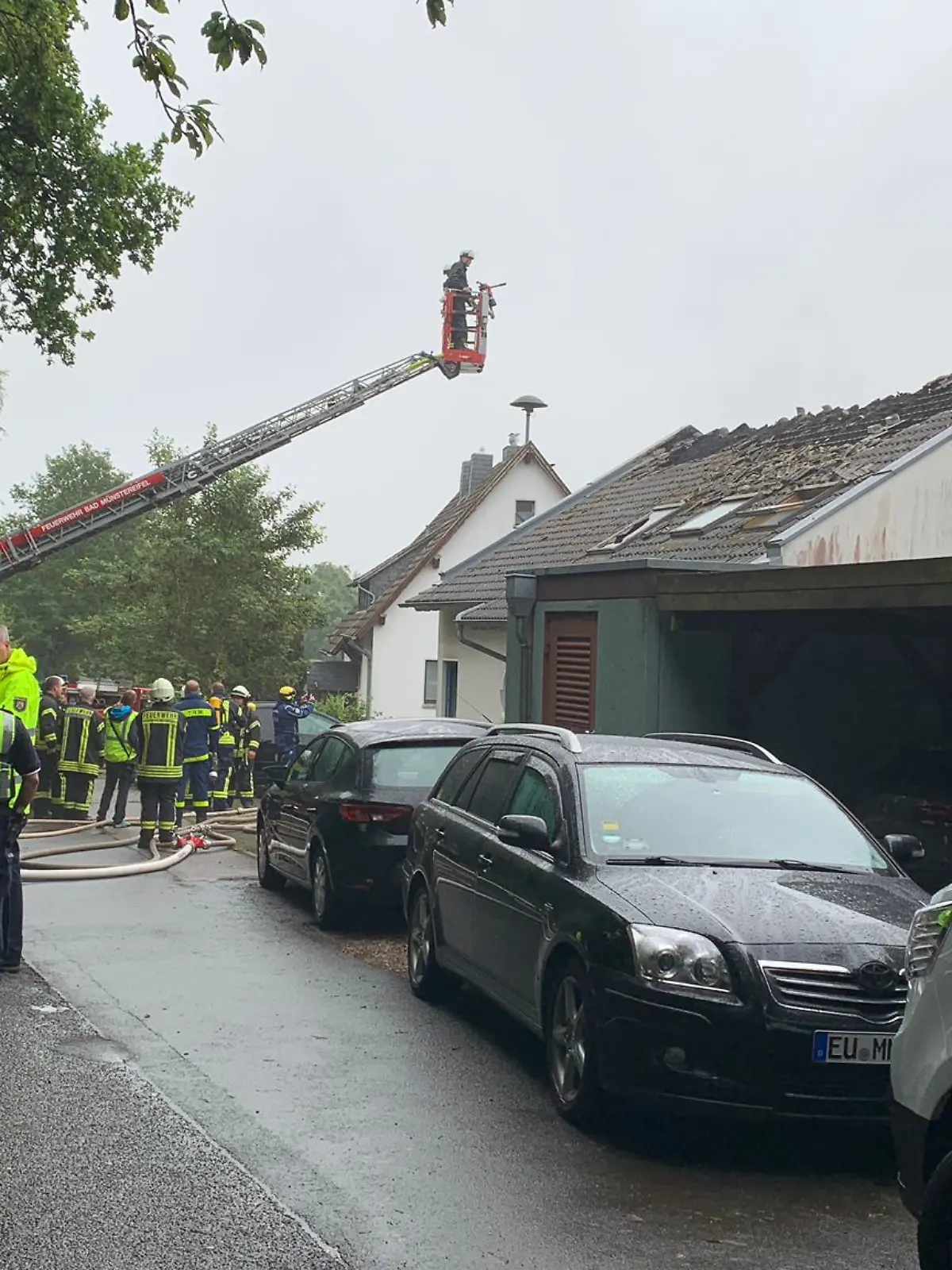Ein beschädigtes Haus, davor Feuerwehr. 