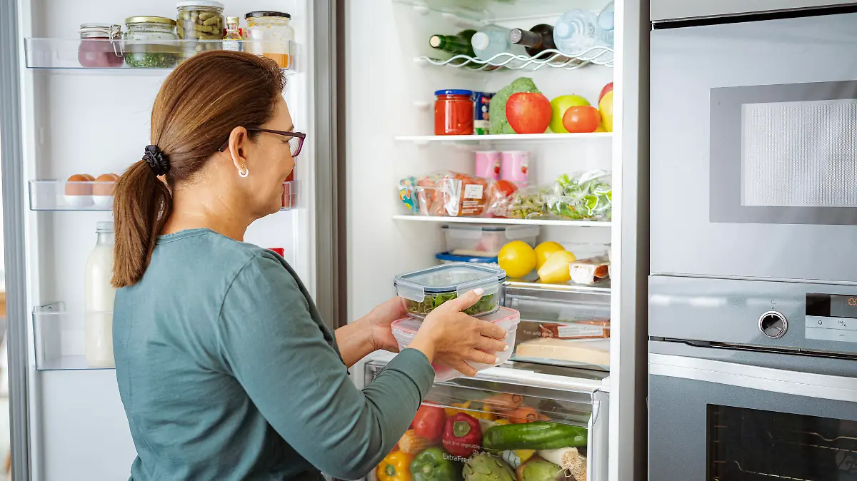 Woman takes containers with raw food from fridge