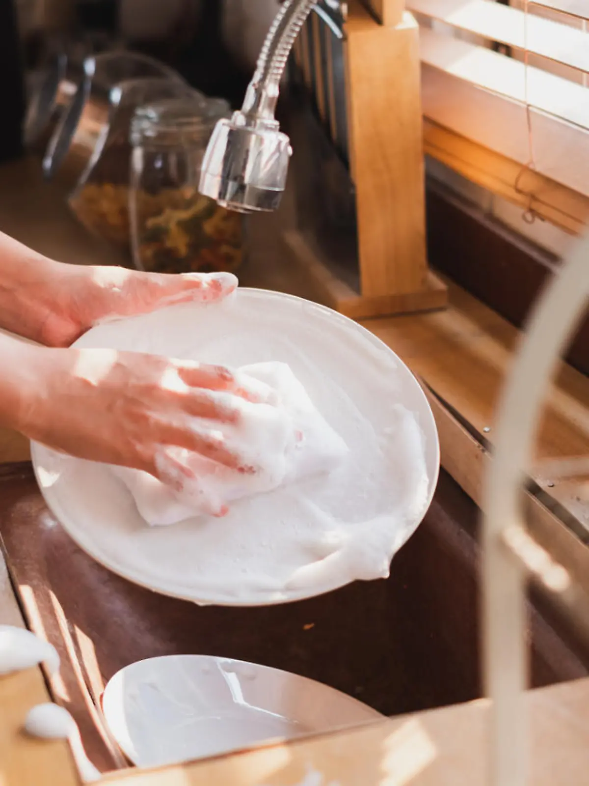 Close up maid housewife washing cleaning dishes in kitchen
