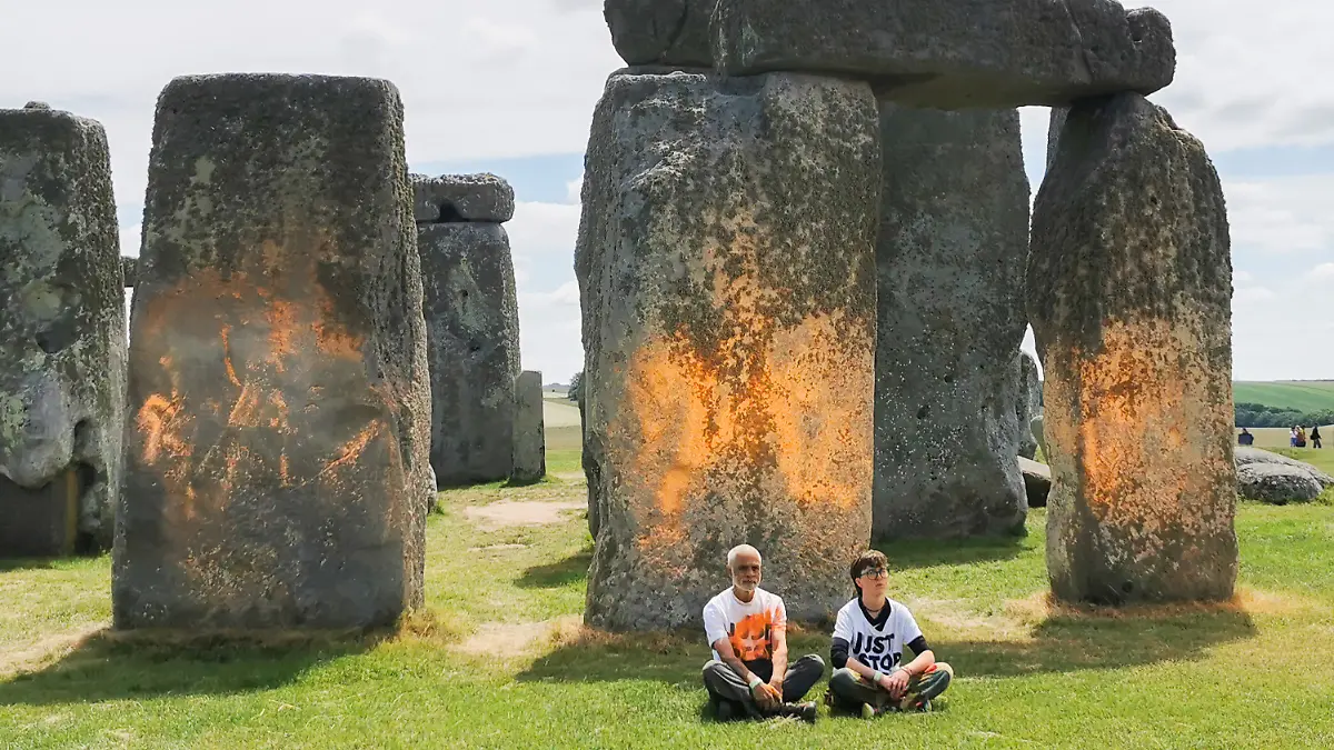 Zwei Männer sitzen vor Stonehenge.