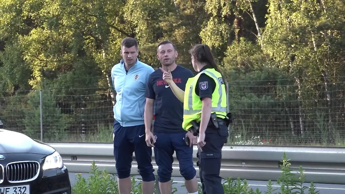 Der Co-Trainer von Kroatien Ivica Olic und Kroatiens Europameisterschaft-Torhüter Dominik Livakovic laufen über die Autobahn 24 neben dem fließenden Verkehr. Eine Polizeibeamtin stoppt sie.