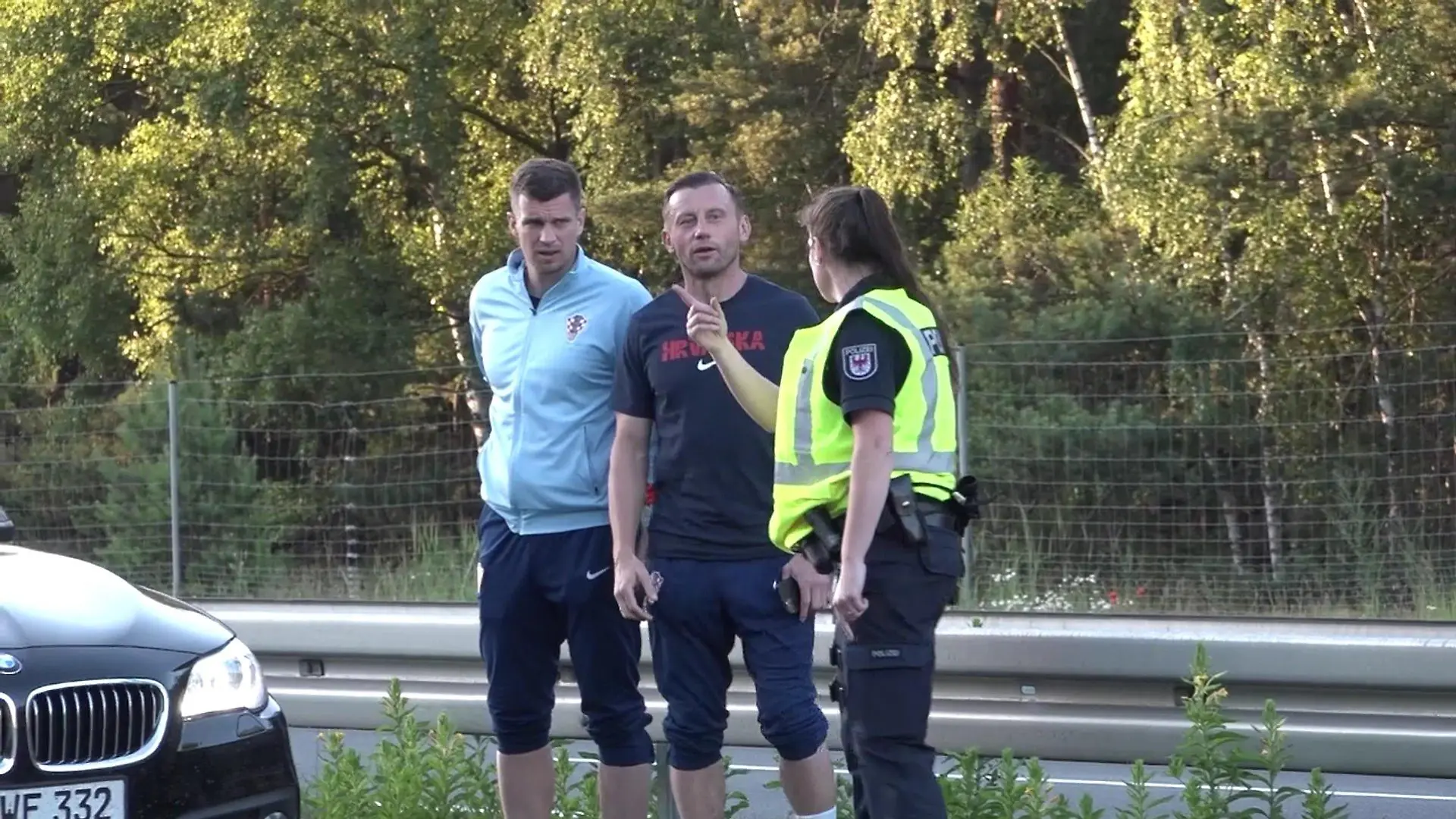 Der Co-Trainer von Kroatien Ivica Olic und Kroatiens Europameisterschaft-Torhüter Dominik Livakovic laufen über die Autobahn 24 neben dem fließenden Verkehr. Eine Polizeibeamtin stoppt sie.