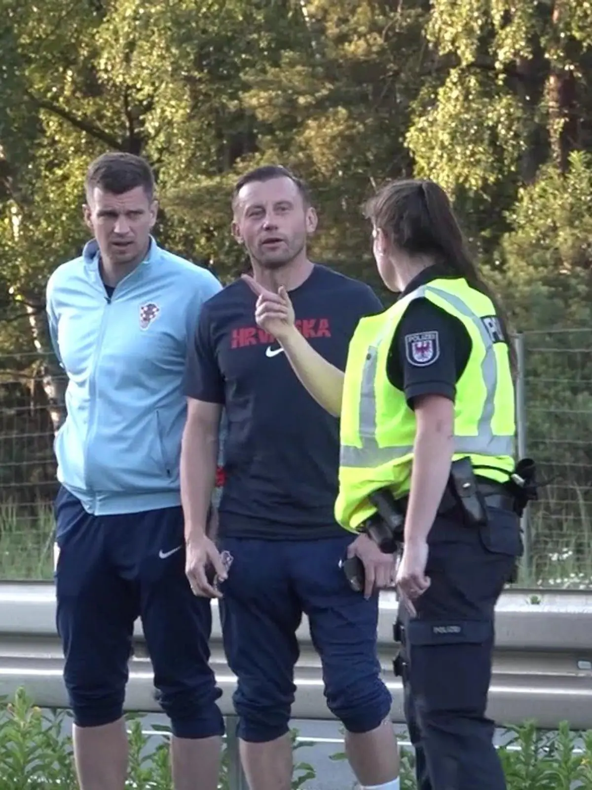 Der Co-Trainer von Kroatien Ivica Olic und Kroatiens Europameisterschaft-Torhüter Dominik Livakovic laufen über die Autobahn 24 neben dem fließenden Verkehr. Eine Polizeibeamtin stoppt sie.