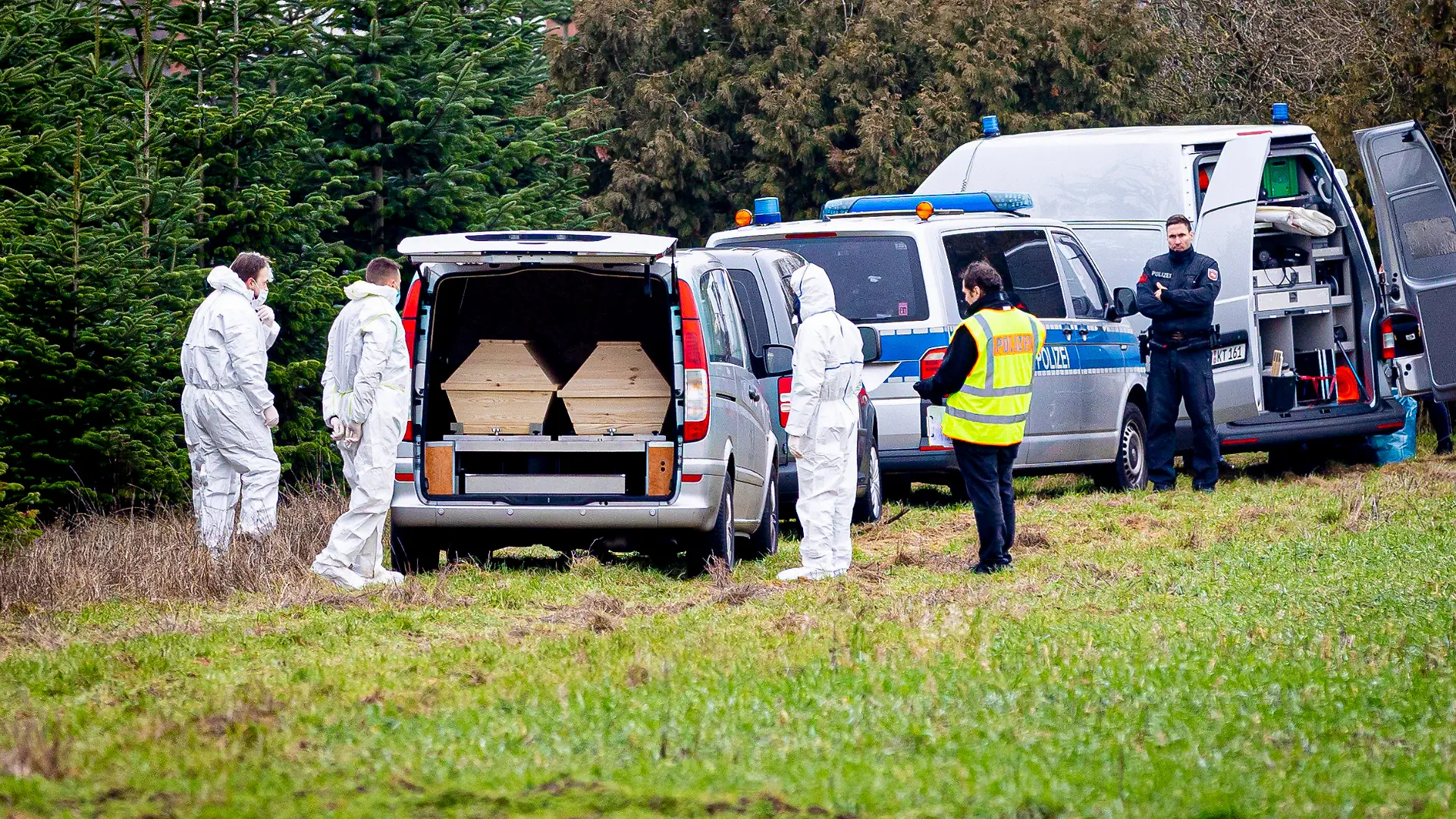 25.01.2023, Niedersachsen, Wunstorf: Mitarbeiter der Spurensicherung der Polizei stehen an einem Leichenwagen, der auf einer Wiese parkt. Auf der Suche nach einer mutmaßlich getöteten Person haben Einsatzkräfte am Vormittag auch ein Waldgebiet im niedersächsischen Wunstorf durchkämmt. Foto: Moritz Frankenberg/dpa +++ dpa-Bildfunk +++