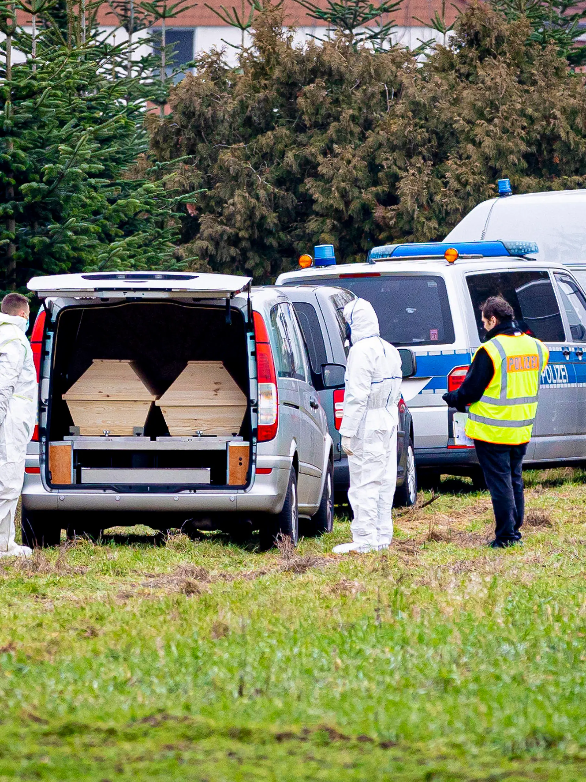 25.01.2023, Niedersachsen, Wunstorf: Mitarbeiter der Spurensicherung der Polizei stehen an einem Leichenwagen, der auf einer Wiese parkt. Auf der Suche nach einer mutmaßlich getöteten Person haben Einsatzkräfte am Vormittag auch ein Waldgebiet im niedersächsischen Wunstorf durchkämmt. Foto: Moritz Frankenberg/dpa +++ dpa-Bildfunk +++