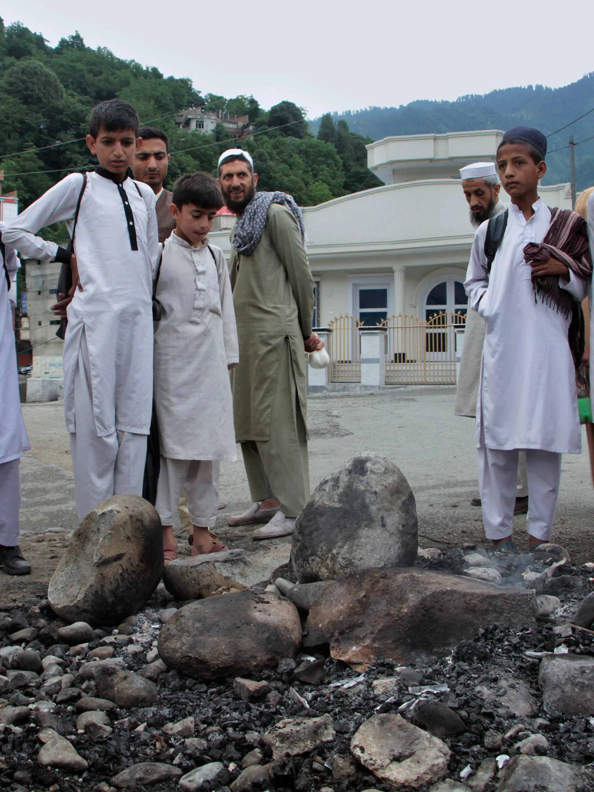 dpatopbilder - 21.06.2024, Pakistan, Madyan: Anwohner blicken auf die Stelle, an der ein muslimischer Mob einen Mann gelyncht und verbrannt hat, weil er angeblich das heilige Buch des Islam, den Koran, geschändet haben soll, in Madyan in der pakistanischen Provinz Khyber Pakhtunkhwa. Die Angreifer setzten auch eine Polizeistation in Brand, in der der Mann in Madyan festgehalten wurde, und verbrannten dort abgestellte Polizeifahrzeuge, wie der örtliche Polizeibeamte Rahim Ullah mitteilte. Foto: Naveed Ali/AP/dpa +++ dpa-Bildfunk +++