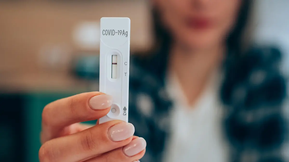 Close-up shot of woman's hand holding a negative test device. Young woman showing her negative Coronavirus/Covid-19 rapid test. Focus is on the test.