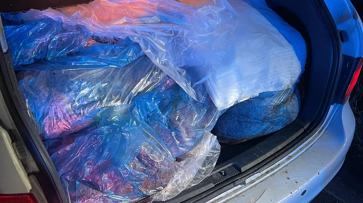 Ein silbernes AUto mit geöffnetem Kofferraum, in dem viele Tüten mit Hackfleisch zu sehen sind.