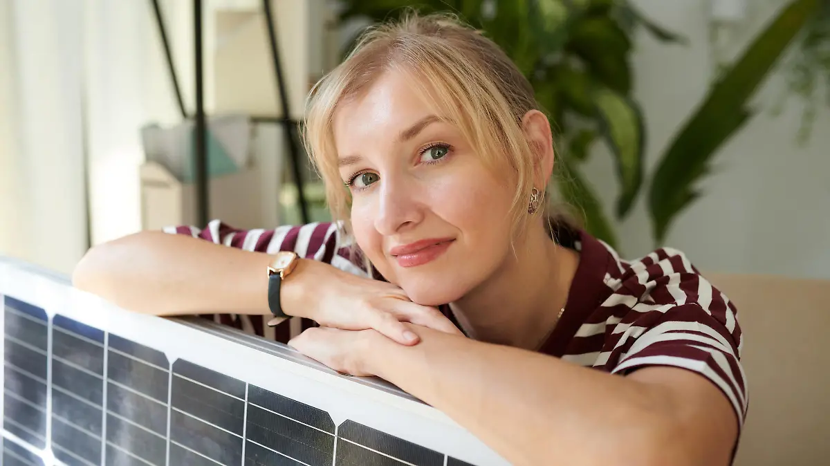 Frau stützt sich auf Solarmodul ab.