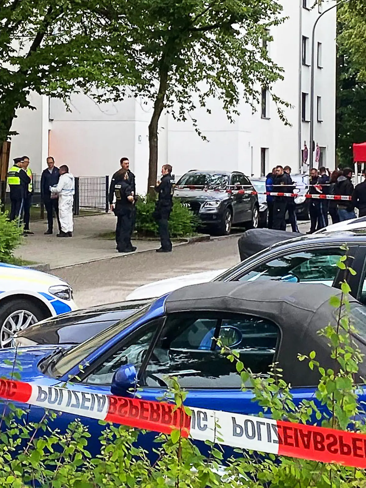 ARCHIV - 03.06.2024, Bayern, München: Einsatzkräfte der Polizei stehen vor einem Mehrfamilienhaus im Stadtteil Milbertshofen. Die Polizei ist zu einem größeren Einsatz ausgerückt. Grund hierfür sei der Fund eines schwer verletzten Mannes, sagte eine Polizeisprecherin. (zu dpa: «Tod nach Streit auf Münchner Straße - Verdächtiger festgenommen») Foto: -/München.TV/dpa +++ dpa-Bildfunk +++