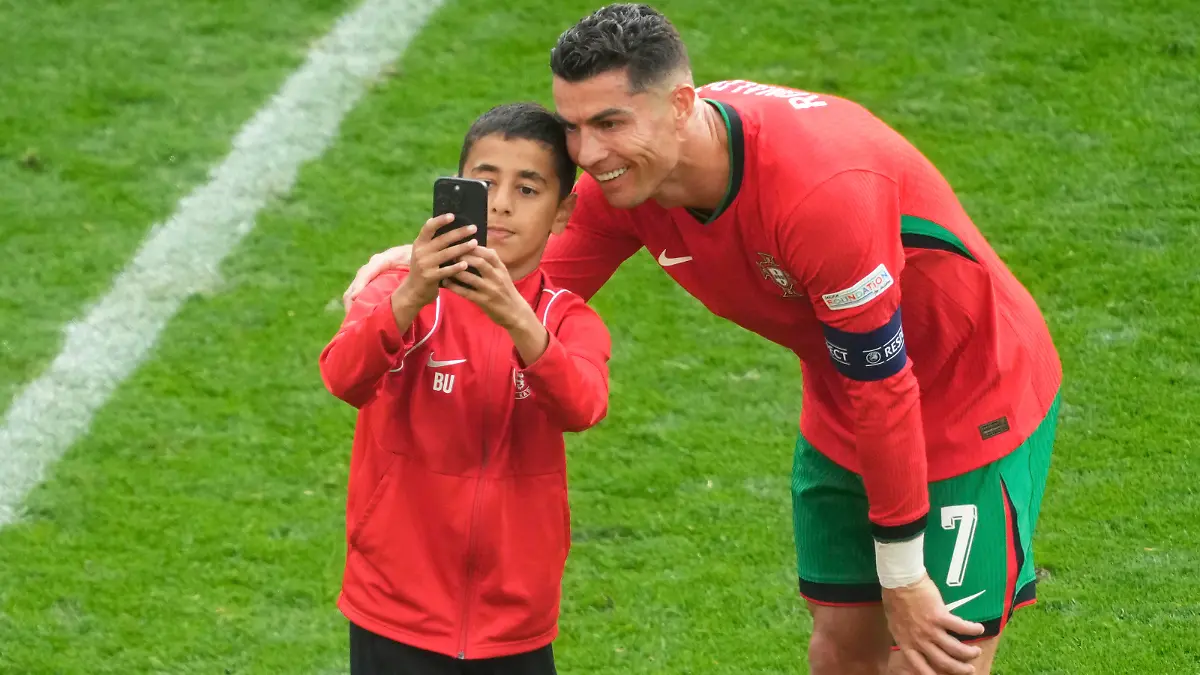 A young pitch invader takes a selfie with Portugal's Cristiano Ronaldo during a Group F match between Turkey and Portugal at the Euro 2024 soccer tournament in Dortmund, Germany, Saturday, June 22, 2024. (AP Photo/Michael Probst)