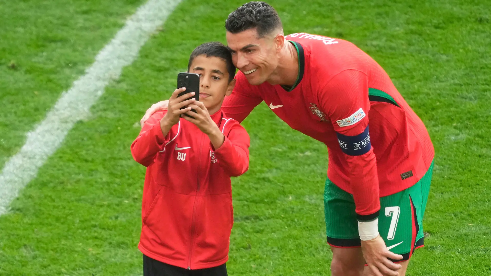 A young pitch invader takes a selfie with Portugal's Cristiano Ronaldo during a Group F match between Turkey and Portugal at the Euro 2024 soccer tournament in Dortmund, Germany, Saturday, June 22, 2024. (AP Photo/Michael Probst)