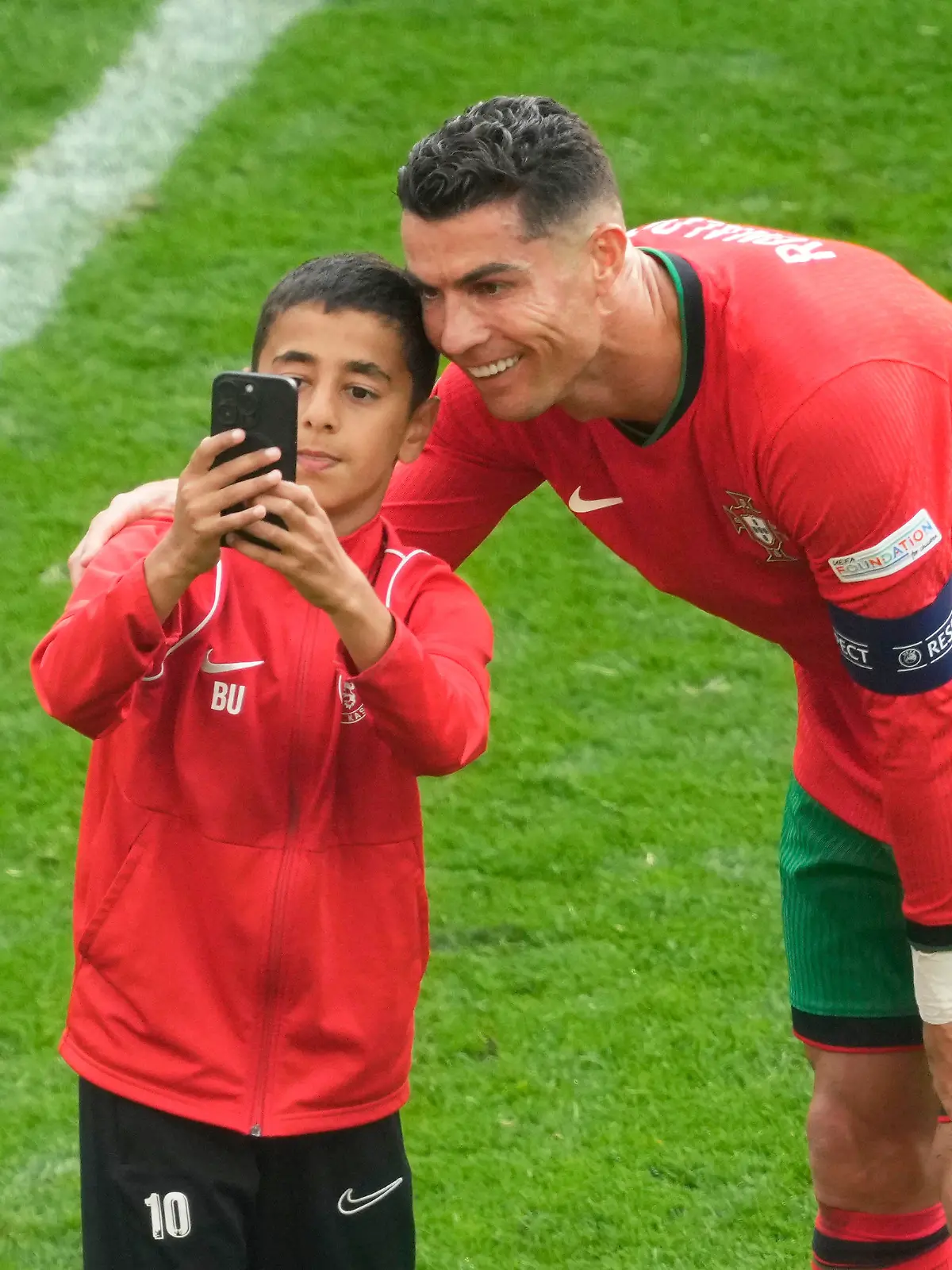 A young pitch invader takes a selfie with Portugal's Cristiano Ronaldo during a Group F match between Turkey and Portugal at the Euro 2024 soccer tournament in Dortmund, Germany, Saturday, June 22, 2024. (AP Photo/Michael Probst)