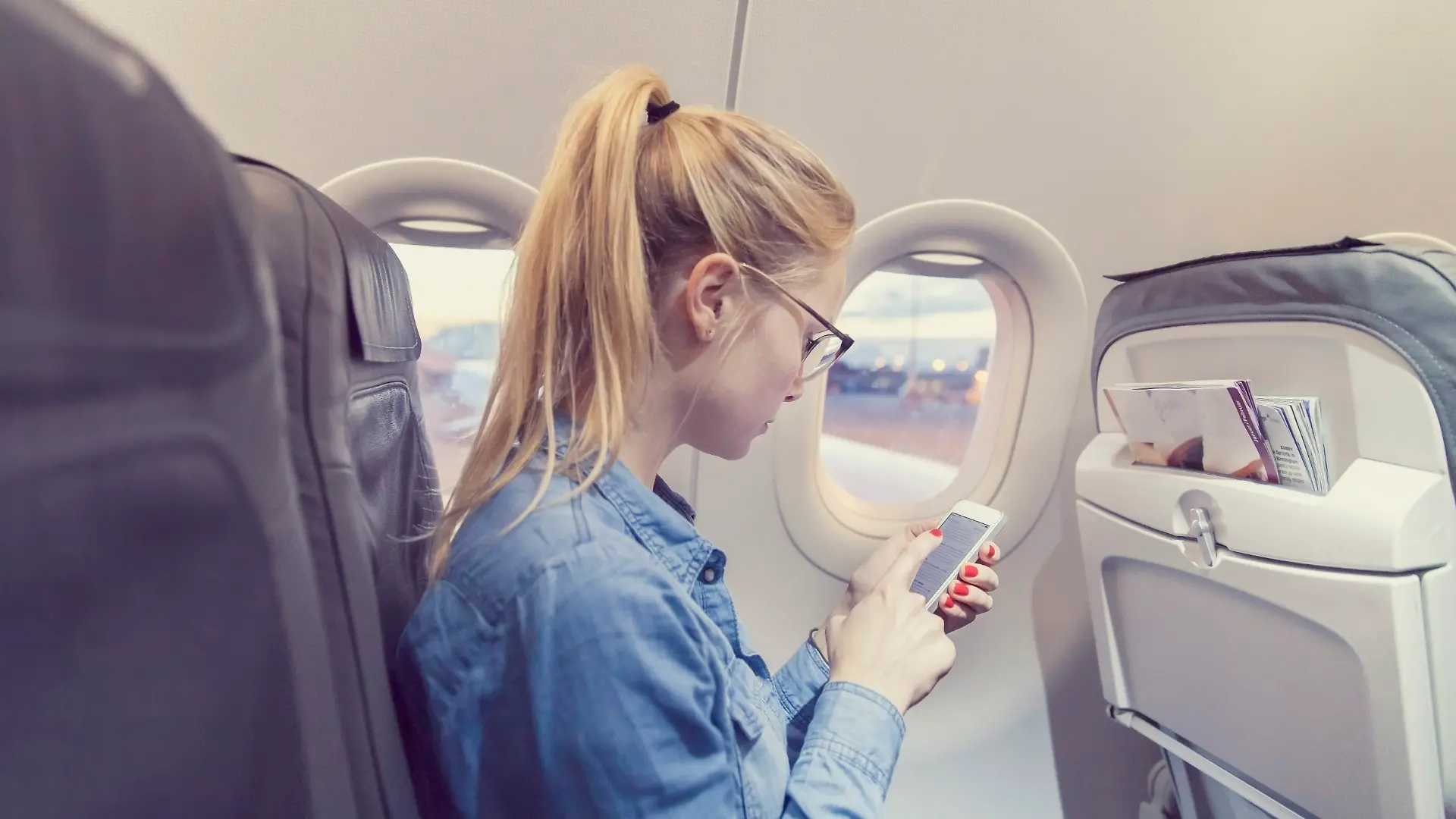 Eine Frau mit Handy im Flugzeug