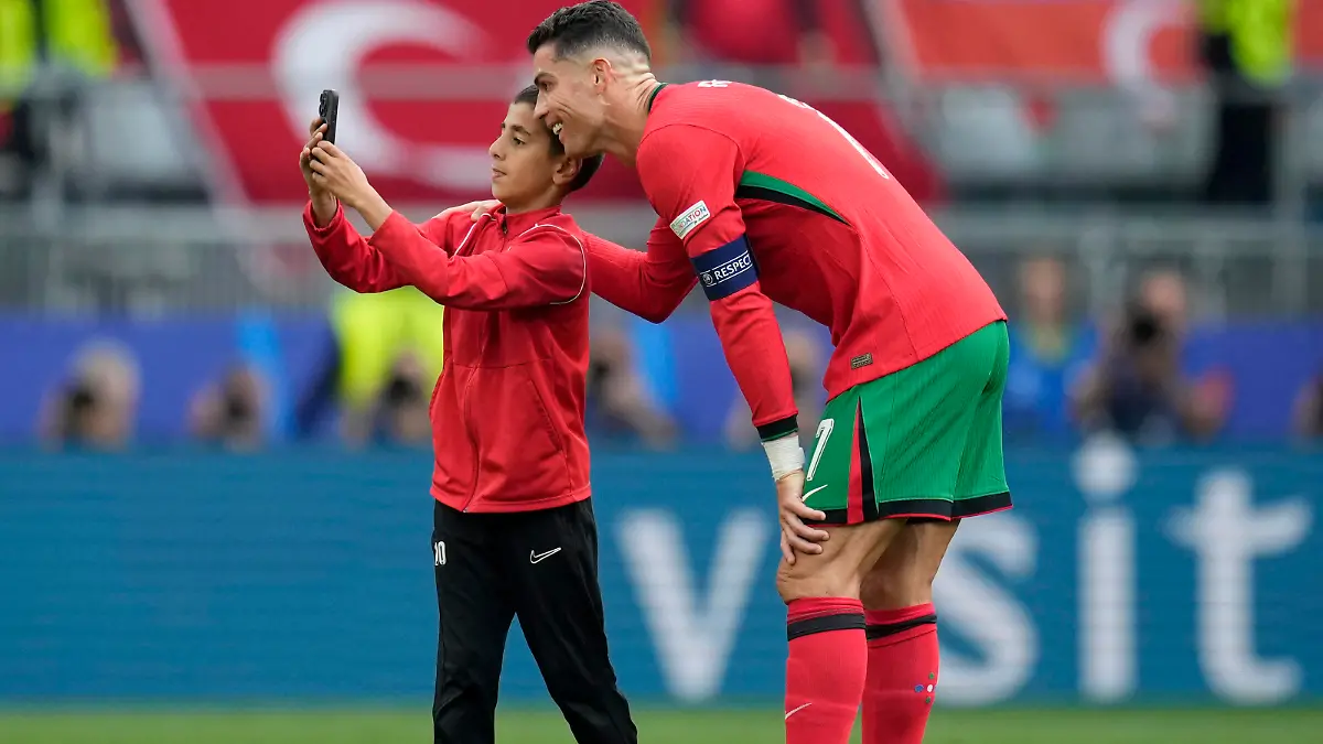 A young pitch invader takes a selfie with Portugal's Cristiano Ronaldo during a Group F match between Turkey and Portugal at the Euro 2024 soccer tournament in Dortmund, Germany, Saturday, June 22, 2024. (AP Photo/Themba Hadebe)