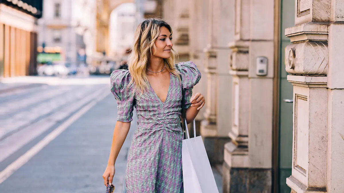 A pretty Caucasian shopaholic with a paper bag going shopping.