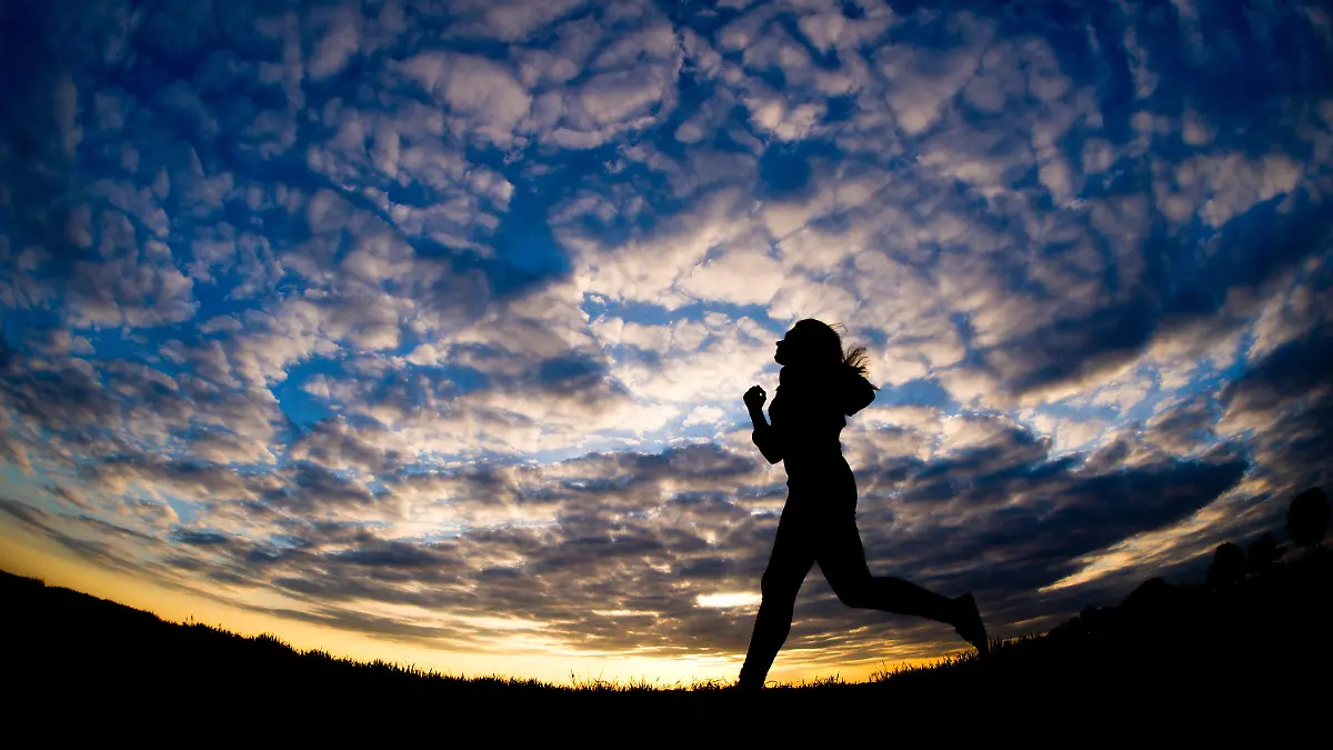 Eine junge Joggerin läuft am 27.05.2015 bei untergehnder Sonne über einen Feldweg bei Echzell (Wetteraukreis/Hessen). Foto: Christoph Schmidt/dpa +++(c) dpa - Bildfunk+++