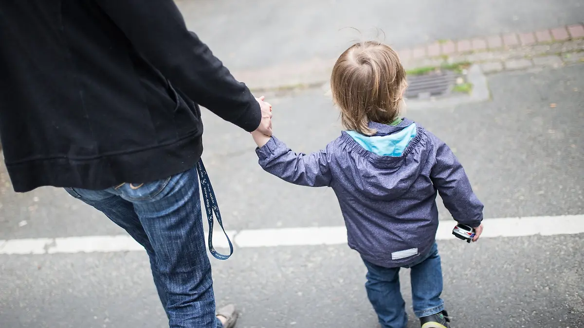 Eine Mutter hält ihren Sohn an der Hand.